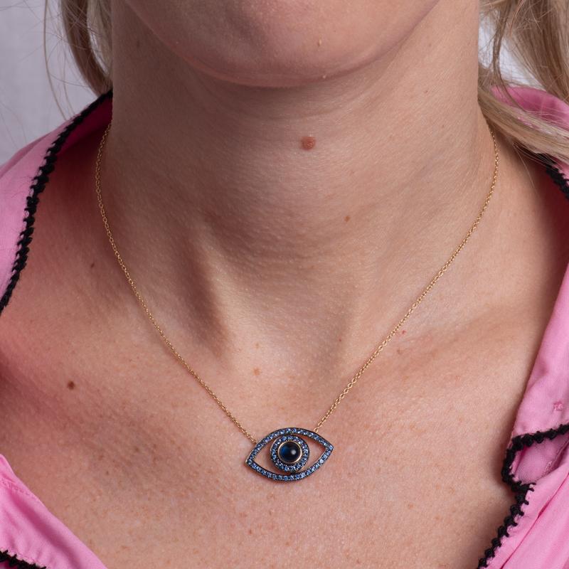 Protect yourself against evil intentions by wearing this evil eye pendant featuring a blue sapphire cabochon accented by 1.32 carat total weight in round blue sapphires set in in 14 karat yellow gold. It is set on an 18