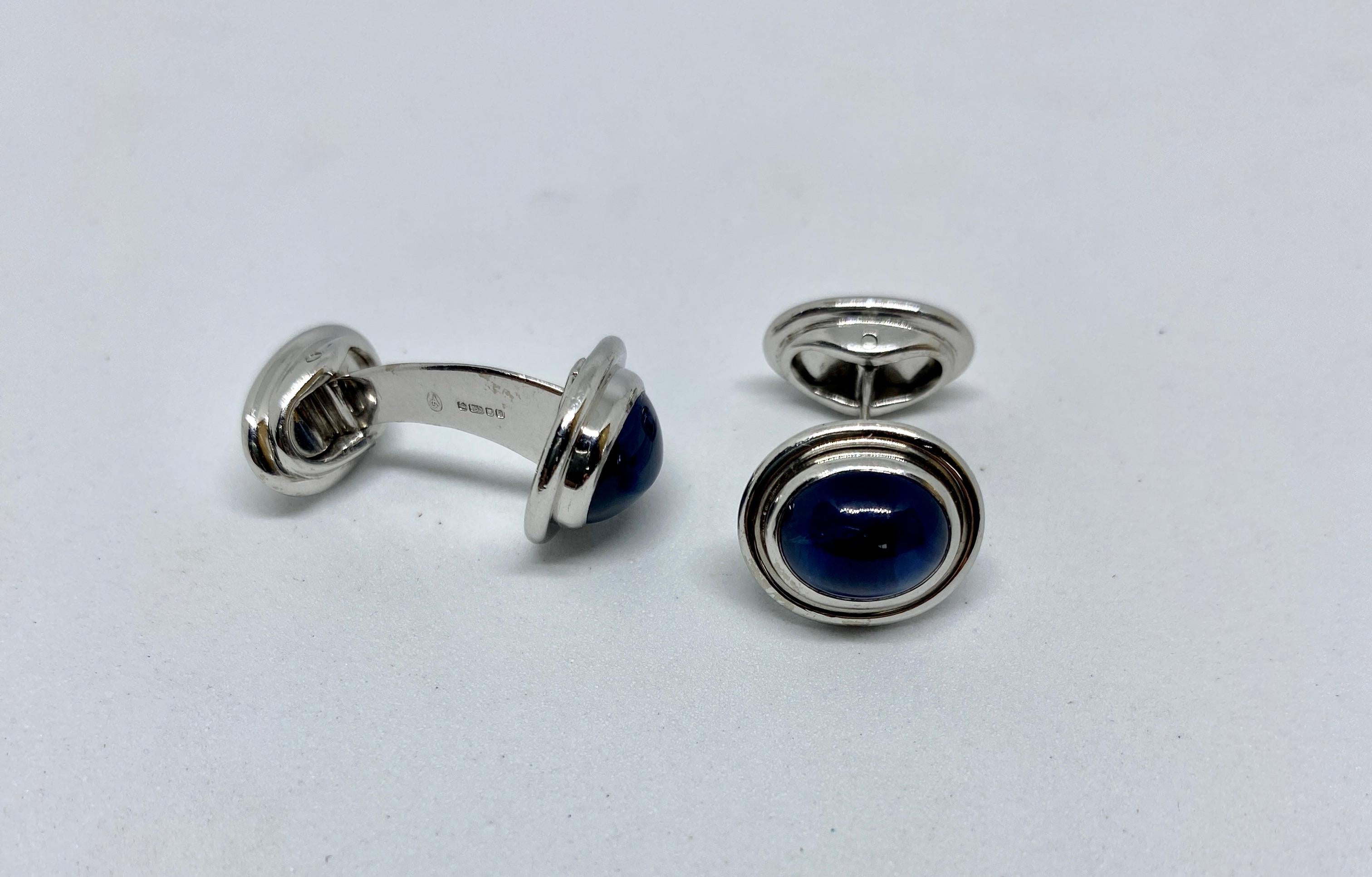 Elegant, tasteful, classic cufflinks in 18K white gold featuring luminous blue oval sapphires and oval-shaped, hinged backs. Retailed by Asprey London, they bear marks for crown jewellers Asprey & Garrard, the London Assay Office, 750 indicating