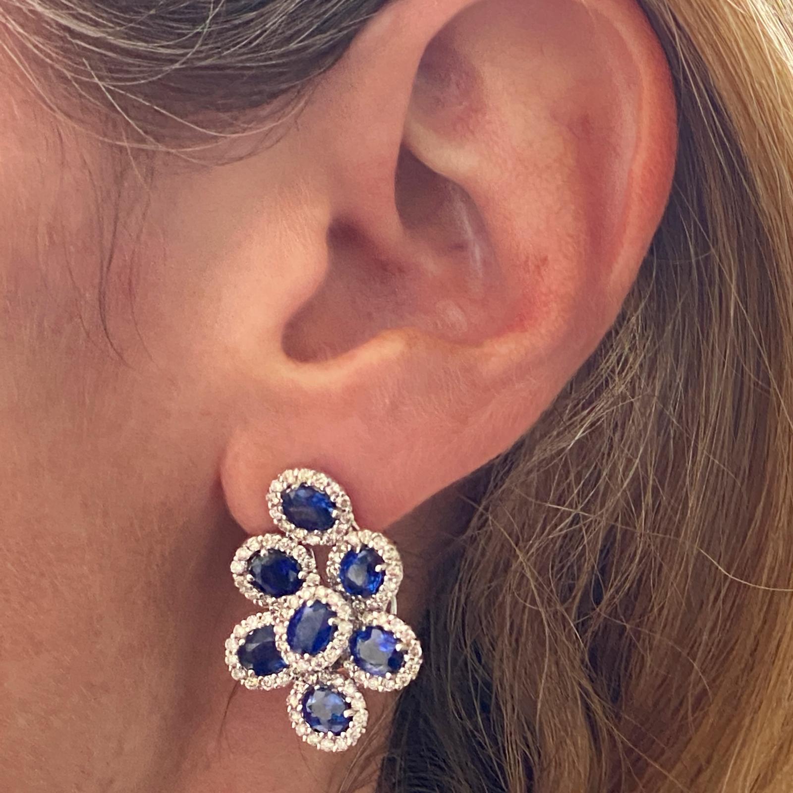 Gorgeous sapphire diamond earrings fashioned in 18 karat white gold. The earrings feature 14 natural blue sapphires weighing 6.30 carat total weight. The sapphires are surrounded by round brilliant cut diamonds weighing 2.18 carat total weight. The