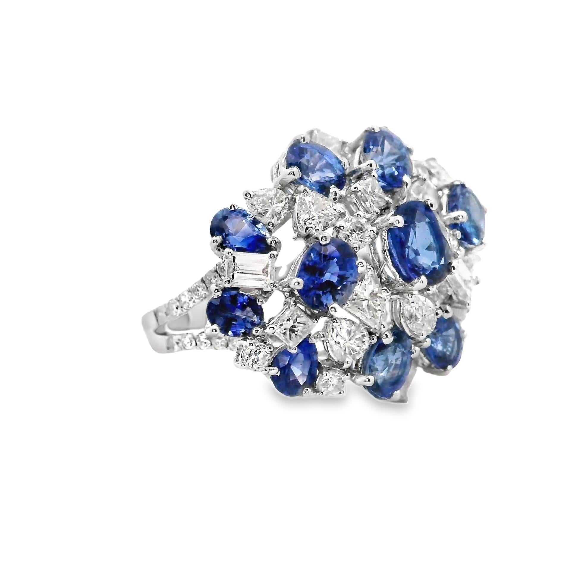 A lovely ring with a cluster of diamonds and gems! The ring features 5.70 carats of vibrant blue sapphires in oval and pear shapes along with 2.14 carats of diamonds cut in various shapes. The stones are set in a cluster sunburst style that makes