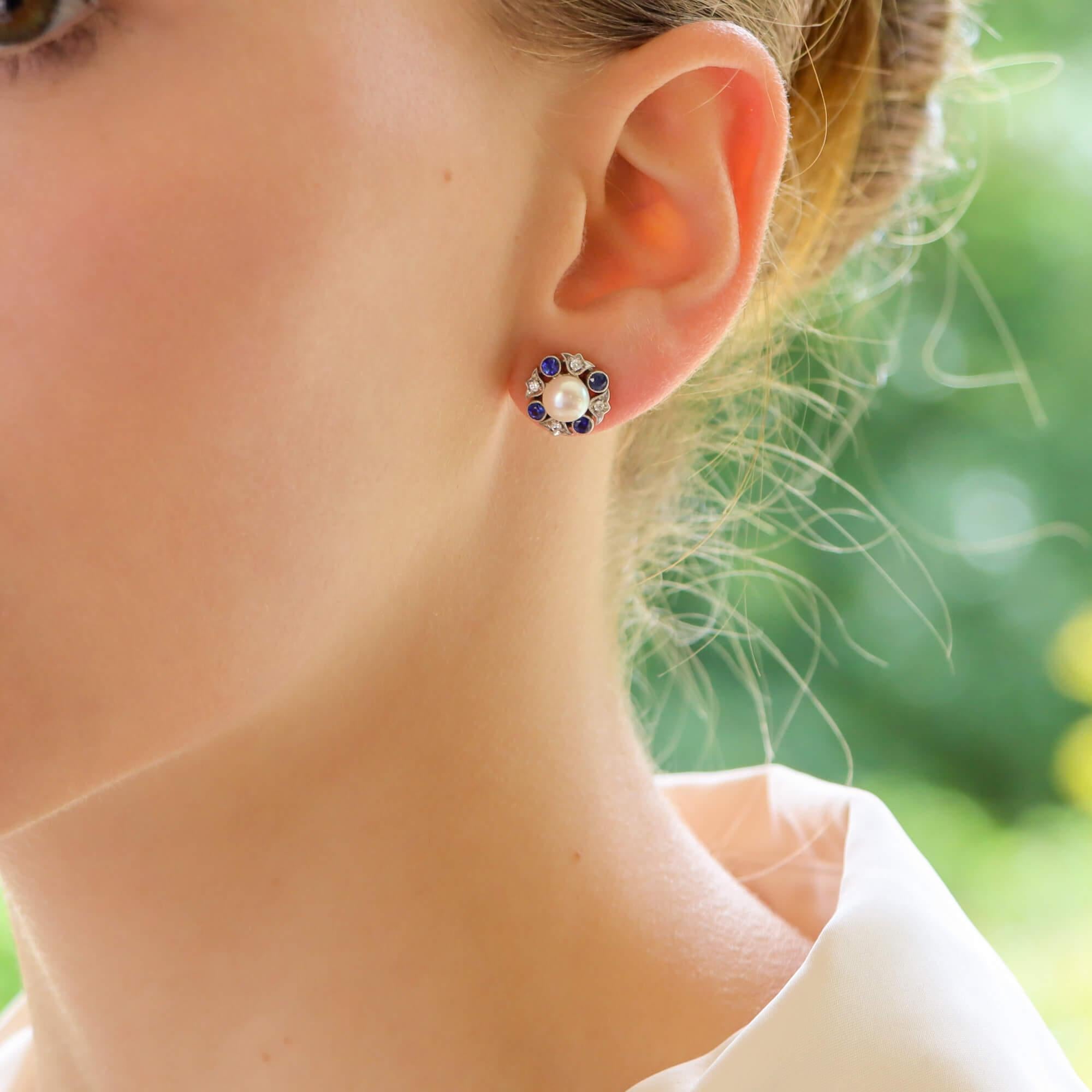 An extremely elegant pair of pearl, diamond and blue sapphire cluster earrings in 18k white gold.

Each earring centrally features a lustrous white cultured pearl and is surrounded by an abstract halo of millegrain diamonds and blue sapphires. Both