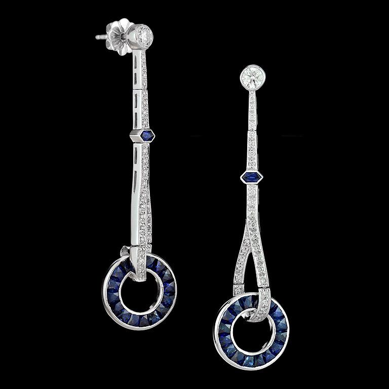 Questi favolosi orecchini a goccia in stile Art Déco con zaffiri blu e diamanti sono caratterizzati da zaffiri incastonati a canale di taglio francese e da un cerchietto con bordi in milgrain. Gli orecchini sono appesi a barre dritte di circa 0,80