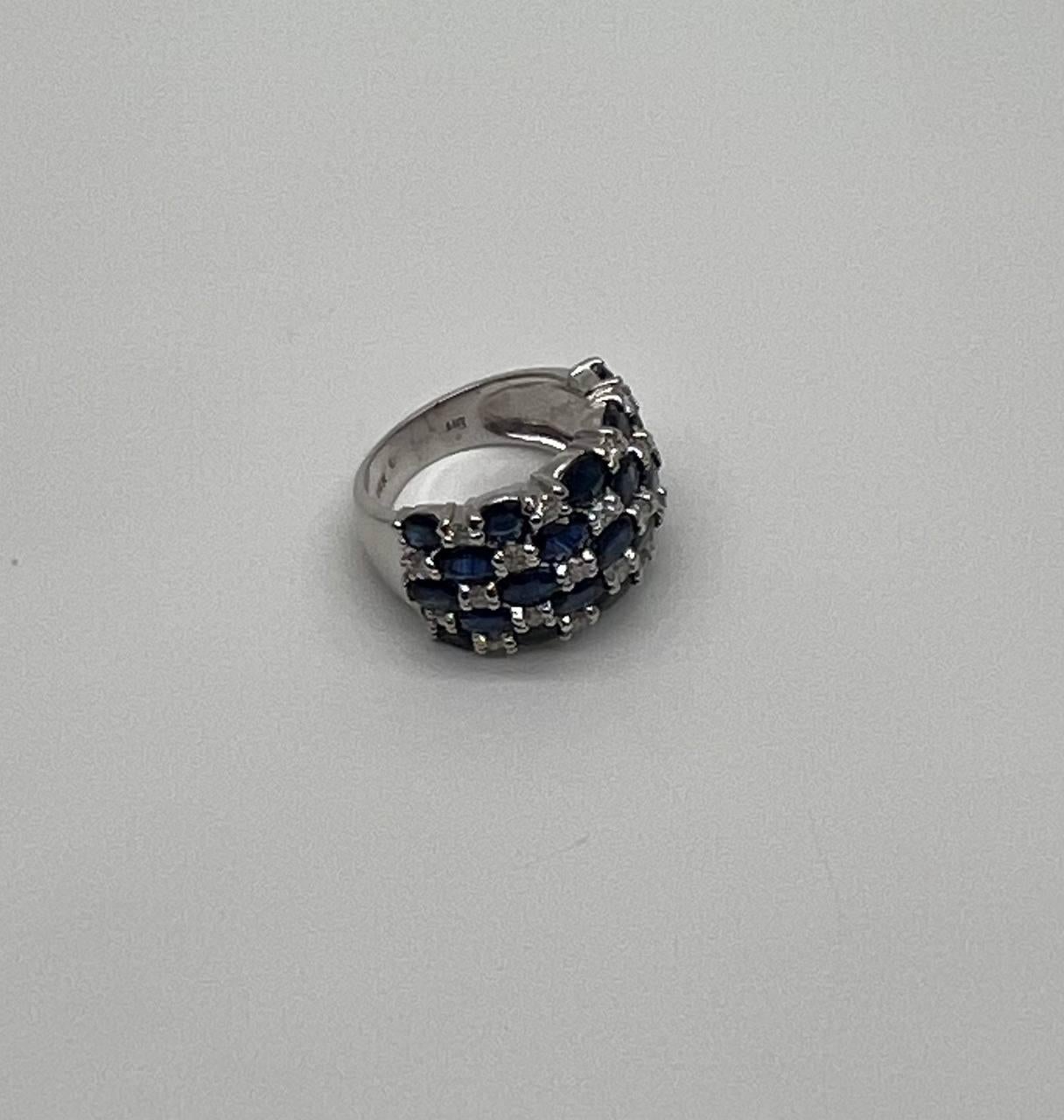 Una sinfonia di profondità, contrasto ed eleganza.
Questo anello di grande impatto mette in mostra un'affascinante disposizione di zaffiri blu intenso, meticolosamente incastonati in un motivo a reticolo. Le ricche sfumature blu sono intervallate da