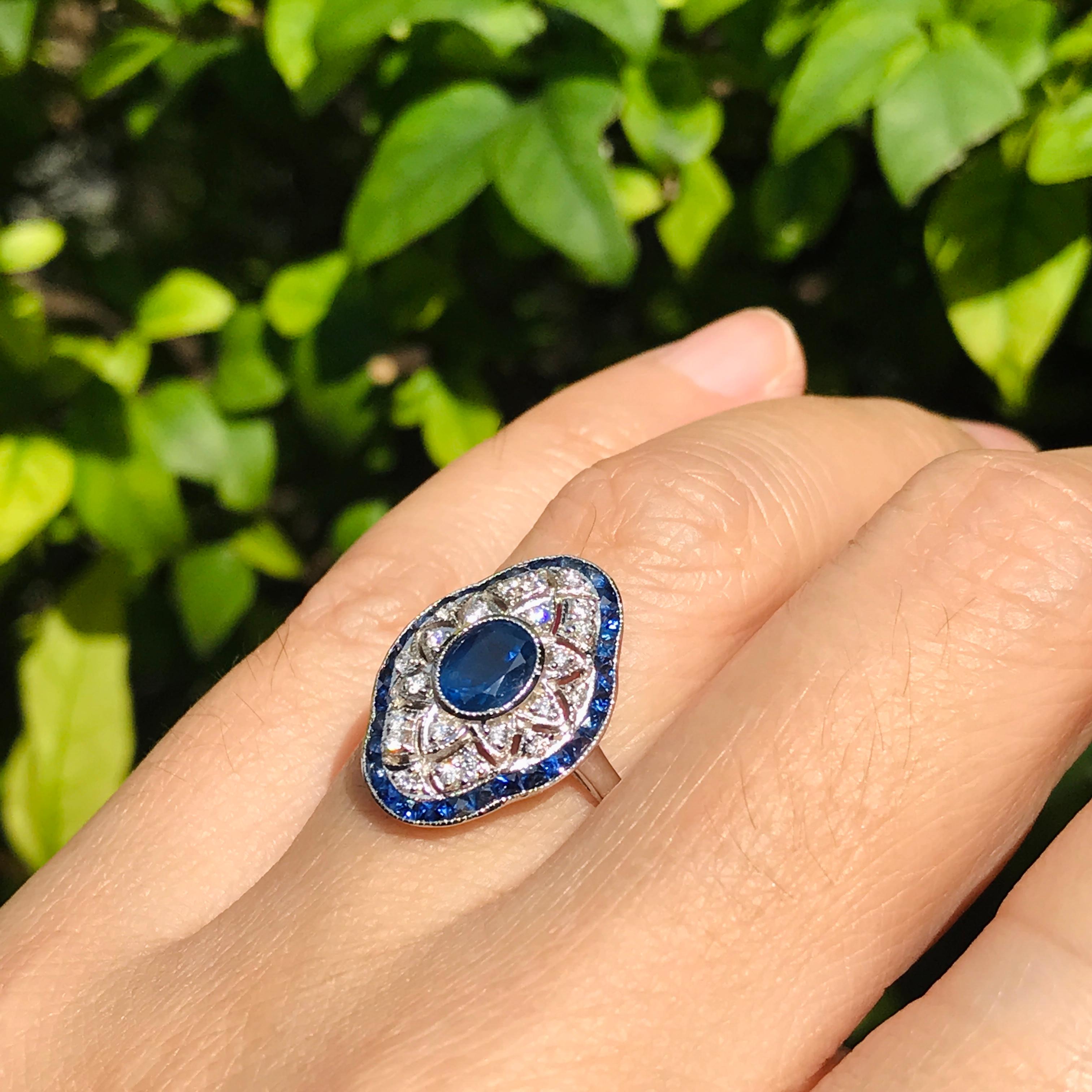 Entra nell'eleganza dell'epoca Art Deco con questo splendido anello traforato con diamante e zaffiro blu in stile Art Deco, meticolosamente realizzato in lussuoso oro bianco 18 carati. Al centro si trova un affascinante zaffiro blu di forma ovale,