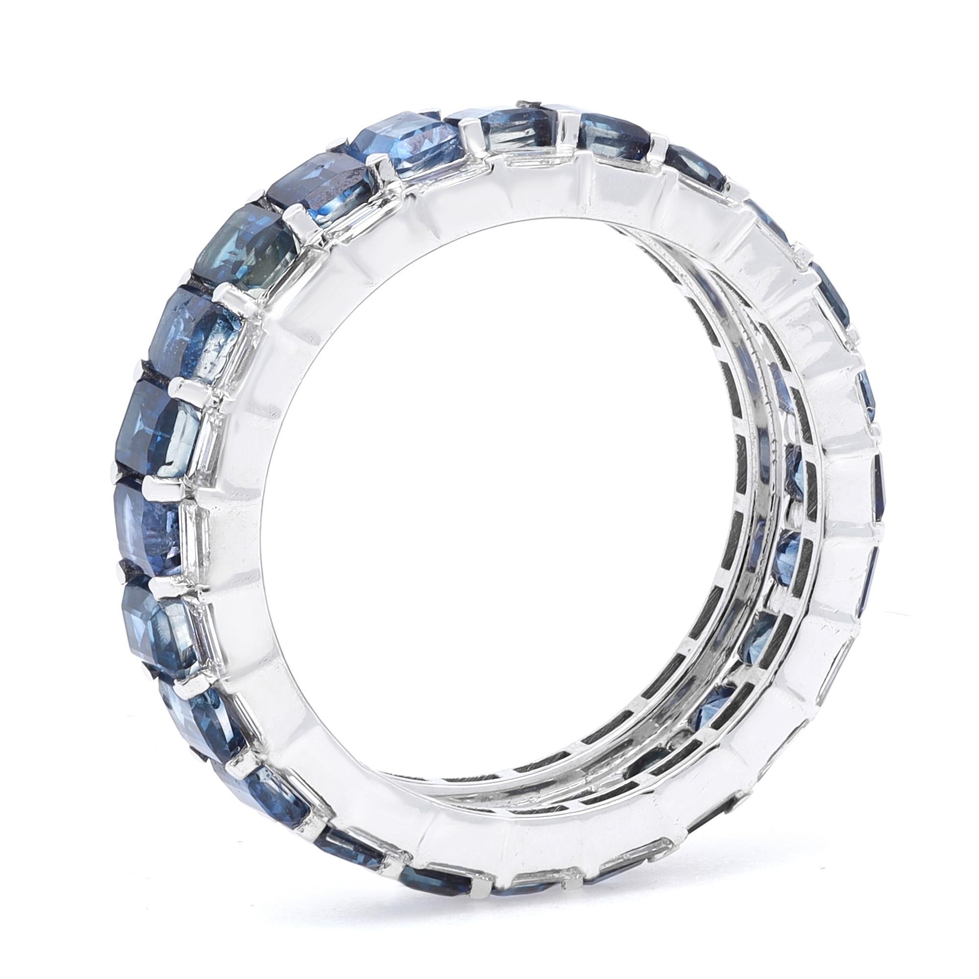 This stunning eternity band features prong set emerald cut blue sapphires as a center row with Baguette cut diamonds outline. The stones are beautifully circling all the way around the band and are set in fine 14k white gold. Blue Sapphire total