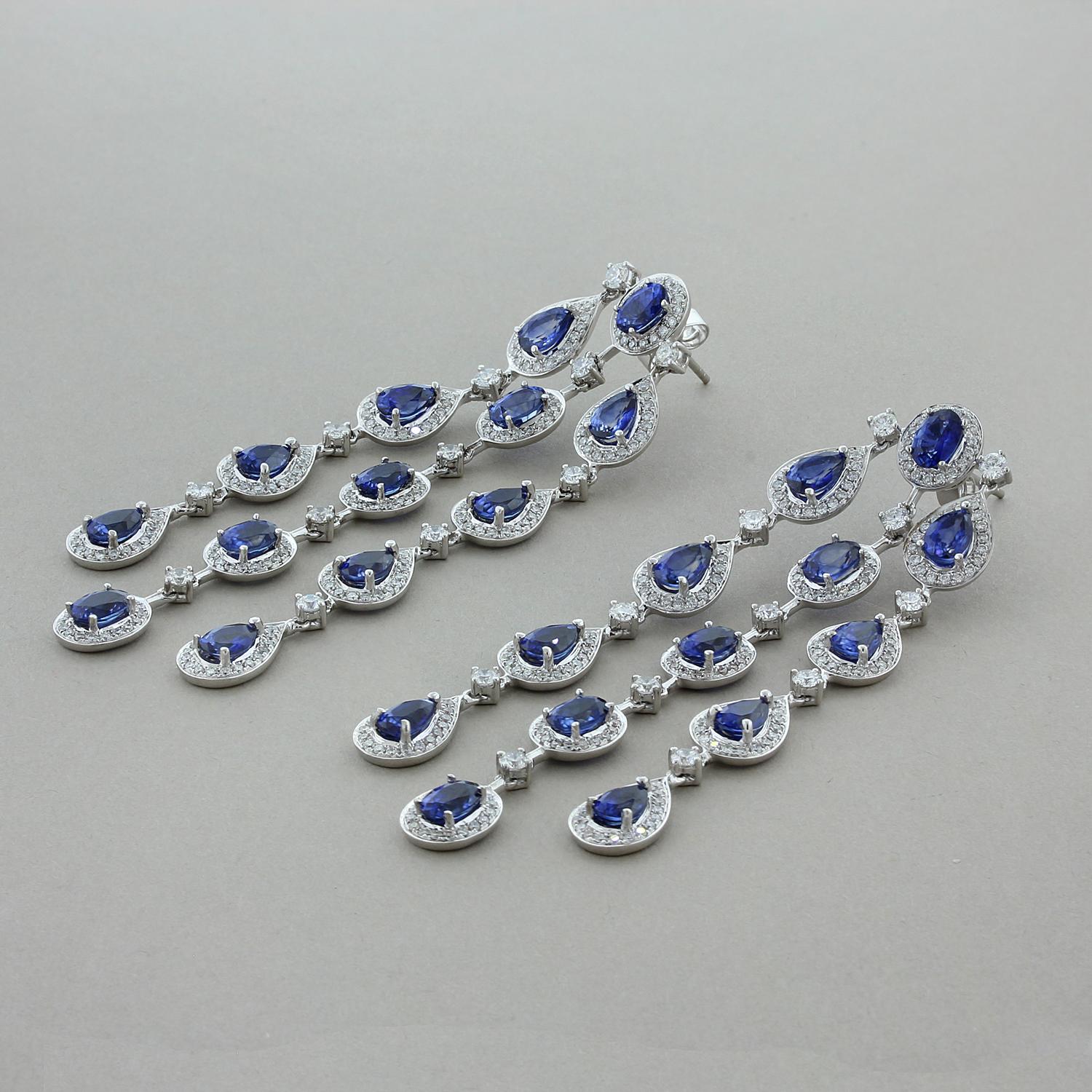 Three chandelier drops of 15.27 carats oval and pear cut blue sapphires adorn this pair of dancing earrings. Each of the deep ocean blue sapphires are haloed and linked by 4.36 carts of VS quality colorless diamonds. The delicate rainfall style of