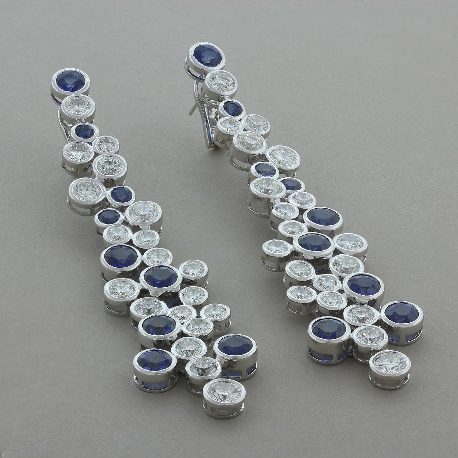 Diese modernen, langen Ohrringe bestehen aus 15,90 Karat runden blauen Saphiren, die von 17,60 Karat funkelnden farblosen Diamanten begleitet werden. Die Lünettenfassung aus 18 Karat Weißgold verleiht diesem Paar flexibler Ohrringe einen klassischen