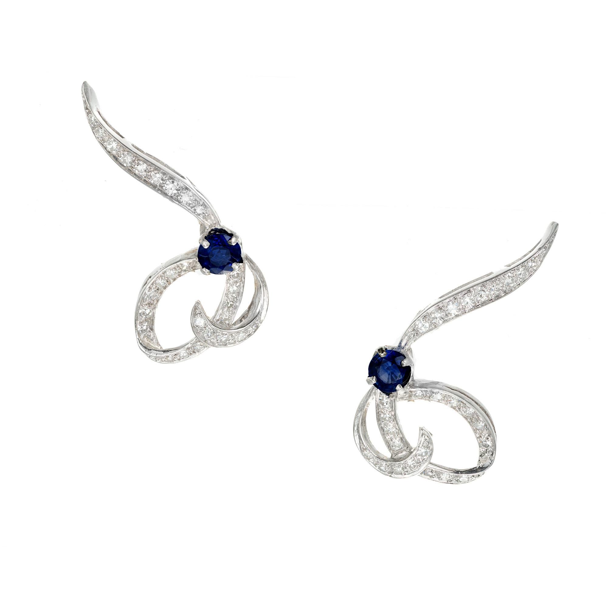 1950's Swirl sapphire and diamond earrings. 2 round sapphires with a total weight of 1.02cts accented with 54 round diamonds approx. total weight .66cts. set in platinum with 14k yellow gold Omega clips and posts. Circa 1950-1960.

2 round Sapphires