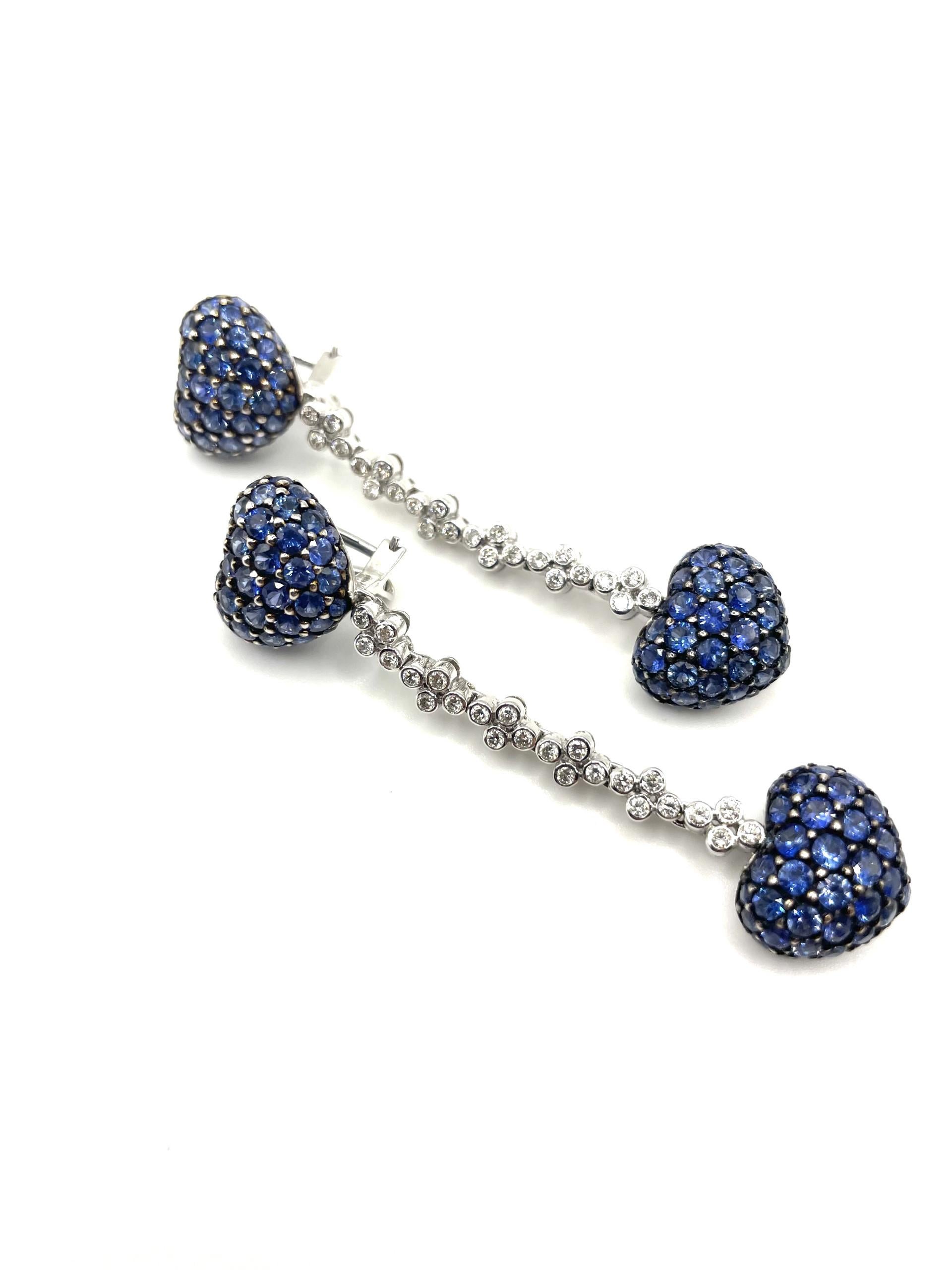 A pair of heart to heart drop earrings set with natural blue sapphires with a black rhodium accent and natural diamonds in 18kt white gold with straight post and omega clip system.

176 natural blue sapphires 9.22ct total weighty

48 brilliant cut