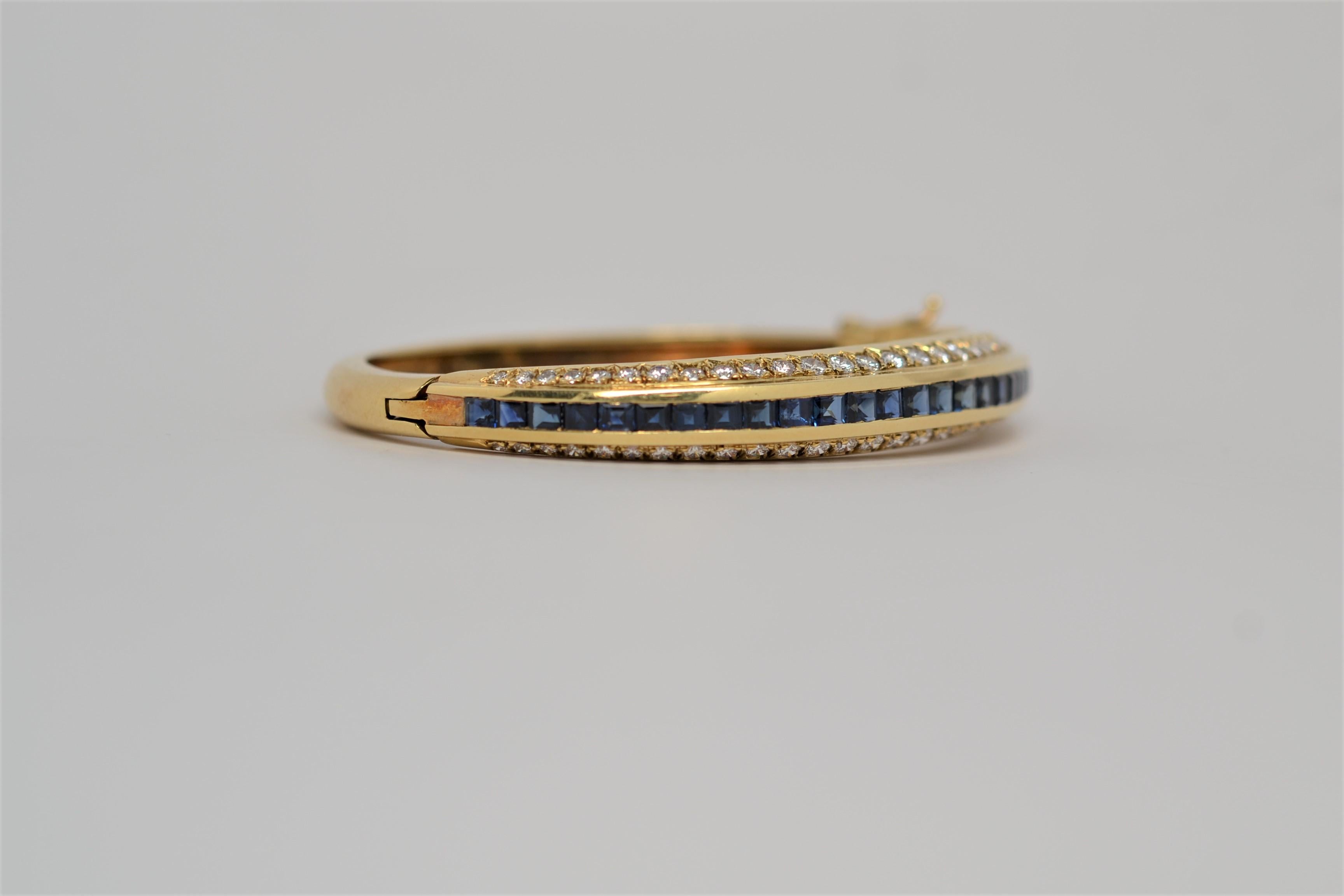 One 18K Yellow Gold bangle bracelet set with Square Cut Blue Sapphires and Round Brilliant Cut Diamonds. The hinged bangle bracelet utilizes a traditional clasp and secondary lock. It is a three row layout set halfway around with Blue Sapphires in
