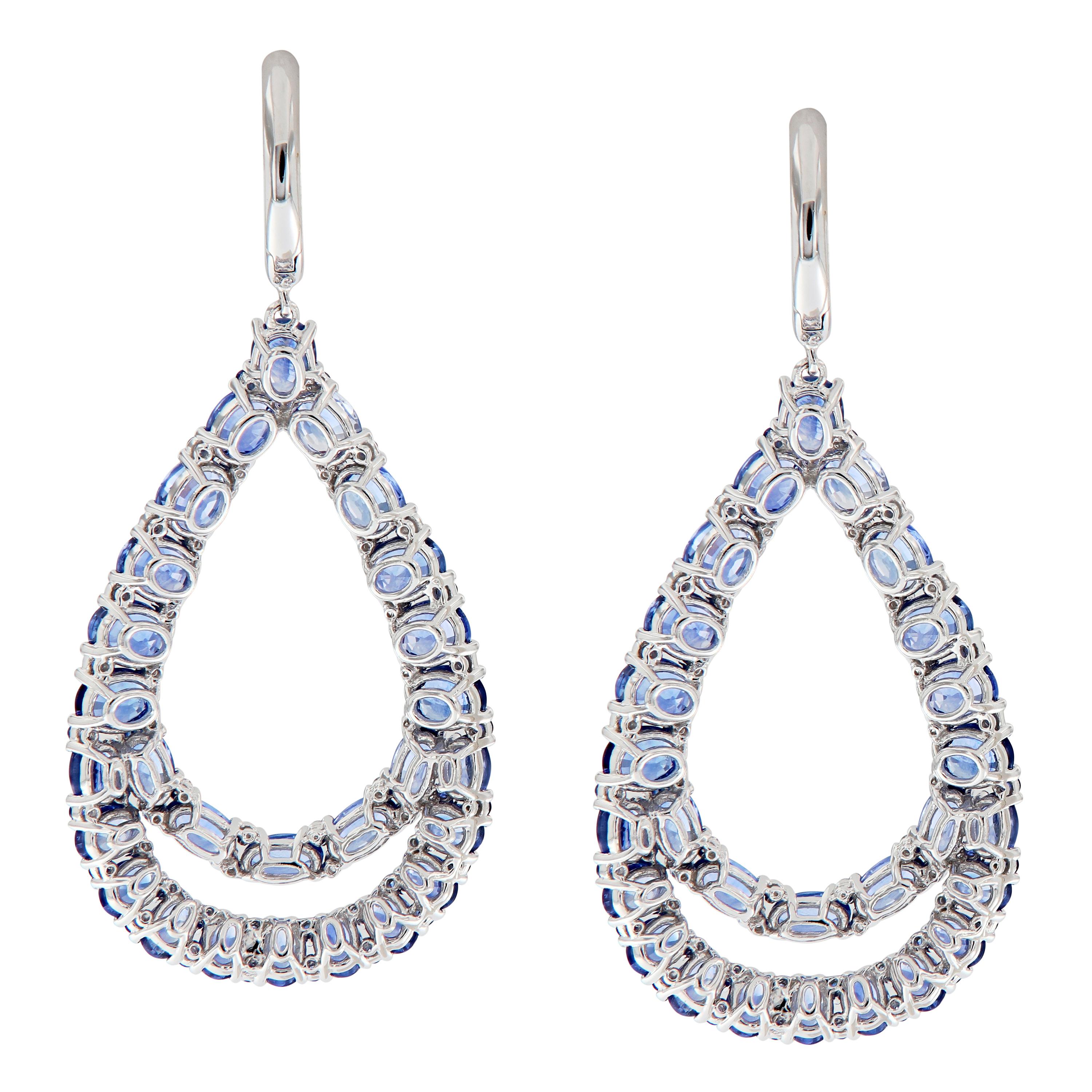 Give her a reason to dress up! These earrings feature a large pear-shaped drop of beautiful blue sapphires and sparkling white diamonds and each drop from a pave set diamond hoop. Earrings are crafted in 18k white gold. Weigh 17.3. grams. 2.25