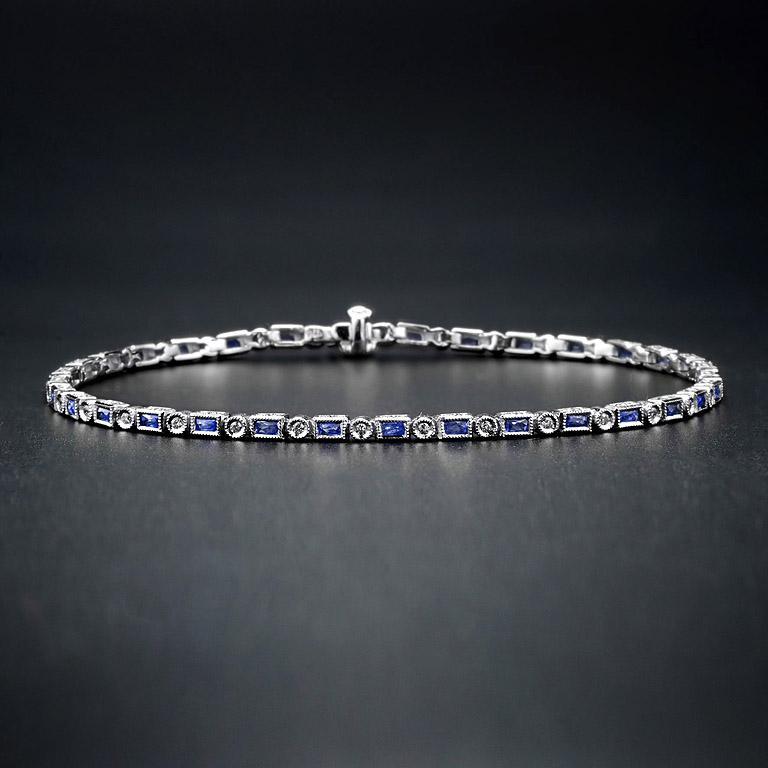 Luxuriant et coloré, ce bracelet présente une alternance de saphir bleu baguette et de diamants ronds de taille brillant. L'or blanc 18 carats confère de la sécurité au style Art Hide classique et un fermoir-boîte à sécurité cachée assure la