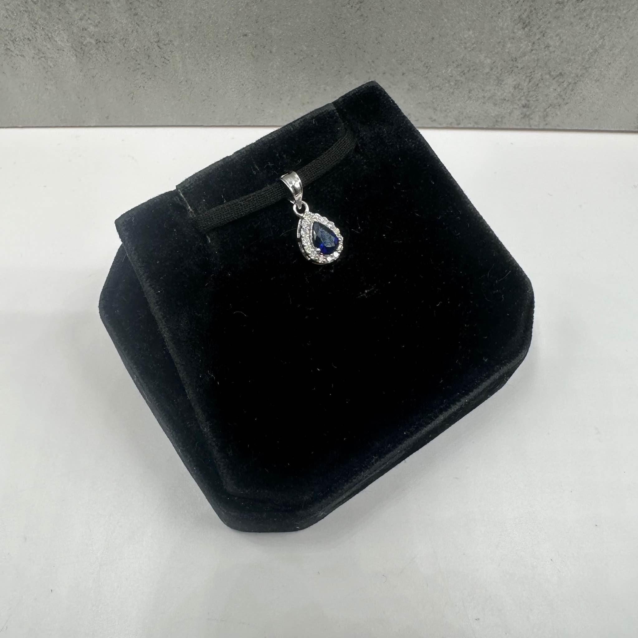 This stunning Blue Sapphire and Diamond Pendant in 14kt white gold features a 5.7x3.8mm pear-cut blue sapphire, complemented by 0.08ctw of natural HI I1 round diamonds for a brilliant contrast. Weighing just 0.8 grams, it is lightweight yet