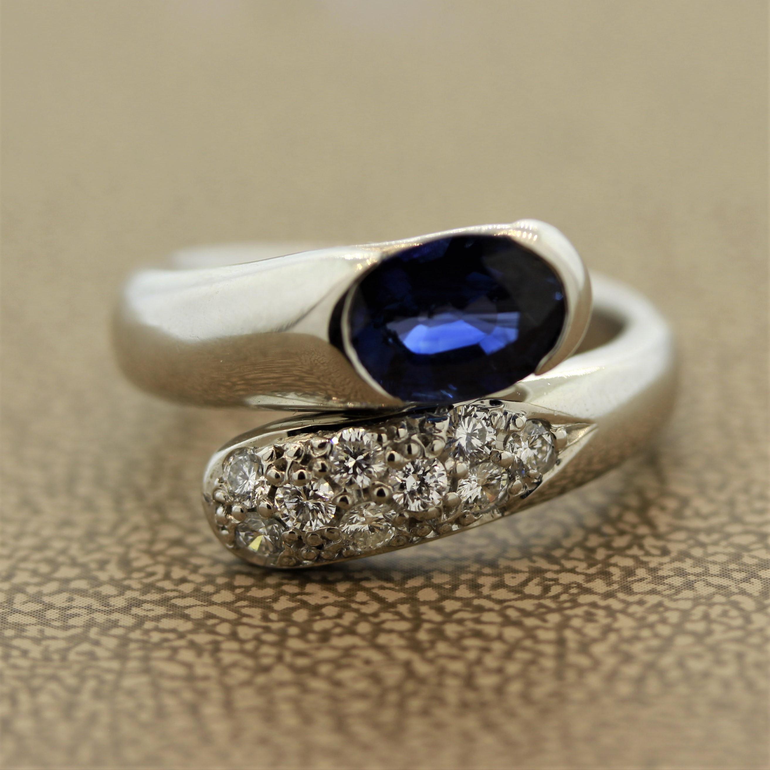An expertly hand-made platinum bypass ring. It features a 1.49 carats oval shaped blue sapphire. It is bezel set with two of its sides free. Accenting the sapphire are 0.33 carats of round brilliant cut diamonds. Weighing a total of 11.4 grams, this