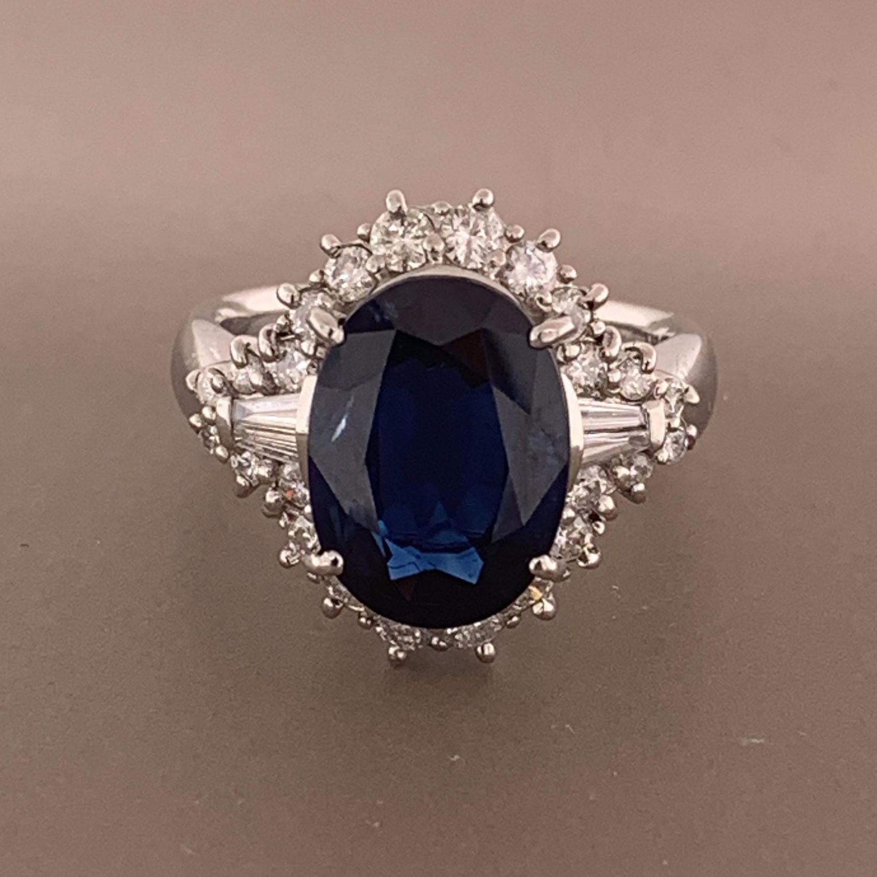 A ring featuring a luscious oval shaped blue sapphire weighing 5.01 carats. It has an even vivid blue color reminiscent of the deep ocean. It is accented by 0.74 carats of round brilliant and baguette cut diamonds creating a unique pattern around