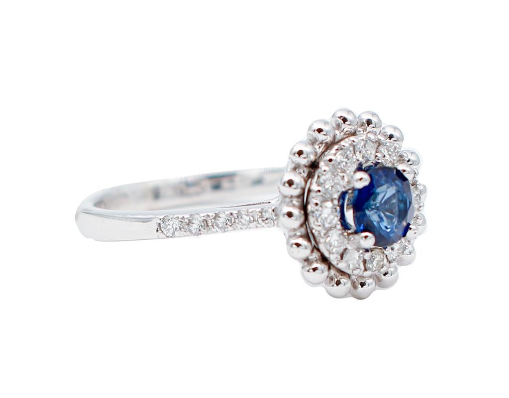 Magnificent  engagement ring created in 18kt white gold and mounted with a central sapphire of 0.62 ct surrounded by 0.36 ct of white diamonds all around it and on the two sides.
Sapphire  0.62 ct / Diameter: 5 mm 
White Diamonds 0.36 ct 
Total