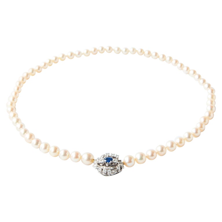 Blue Sapphire, Diamonds and Pearl beaded necklace. The pearl necklace is made with a gorgeous 14 karat white gold clasp set with many very clear diamonds and a blue sapphire. The pearls are round-shaped and bright in color. This necklace has two