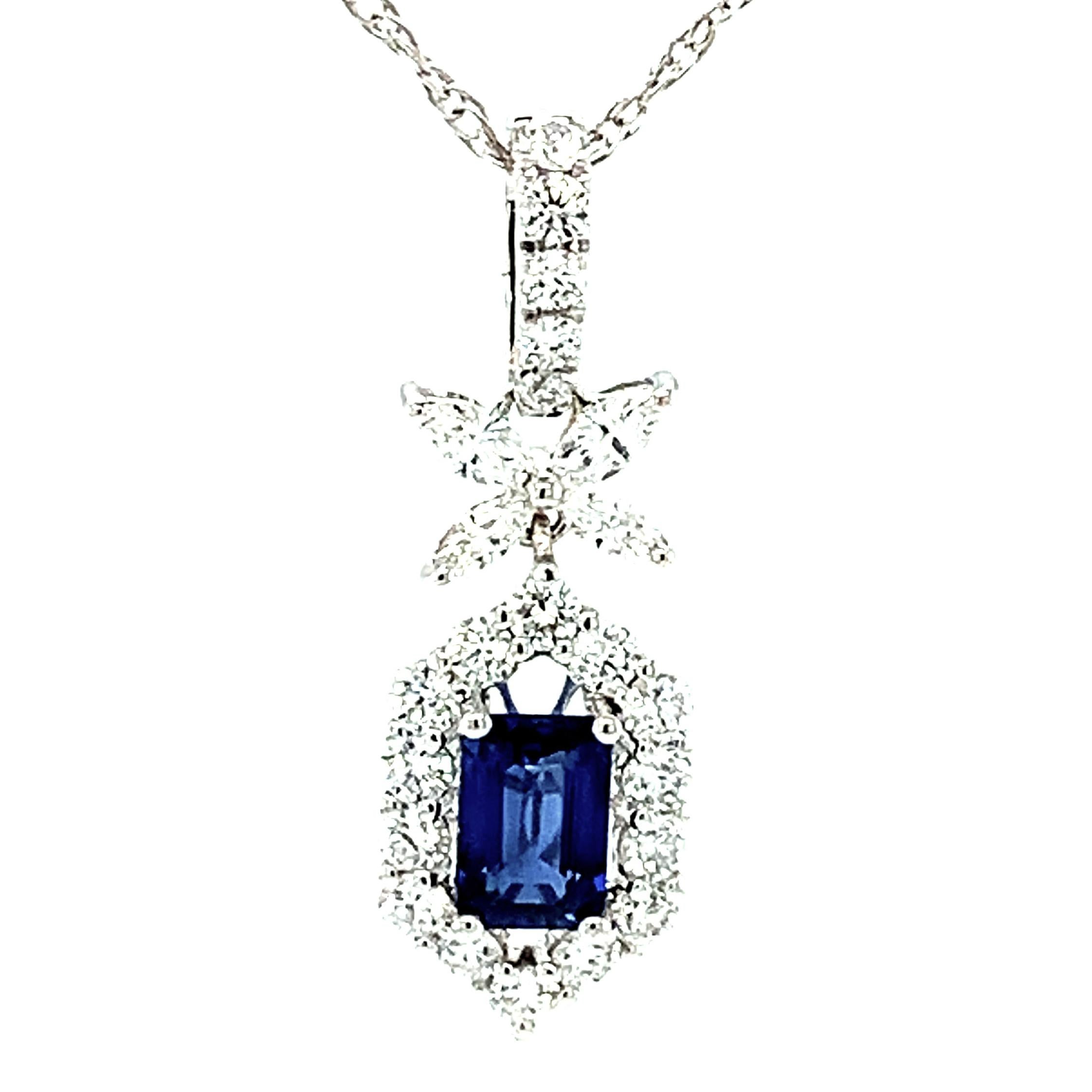 This elegant blue sapphire and diamond necklace features a .61 carat emerald cut gem blue sapphire framed by scintillating white diamonds in a stylish 18k white gold hexagonal design. The sapphire is clean and bright, with wonderfully rich blue