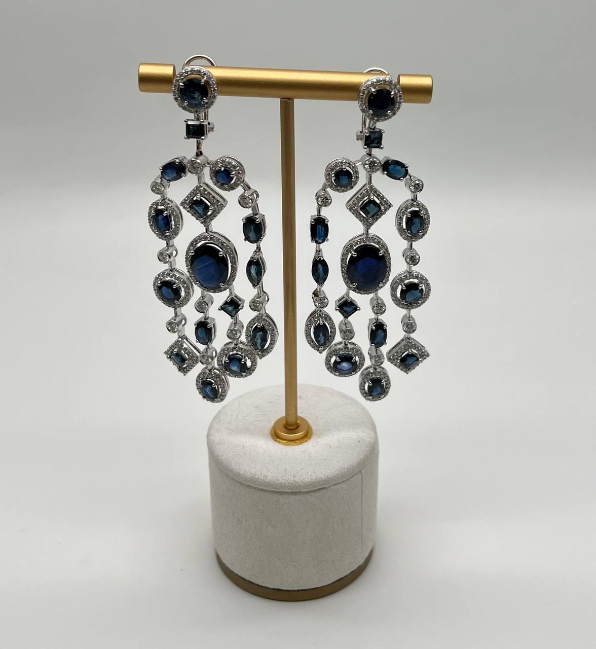 Un paio di splendidi orecchini dal design intricato con zaffiri blu intenso e diamanti scintillanti. Realizzati con precisione, questi orecchini presentano una cascata di pietre ovali e rotonde, elegantemente incastonate in una cornice scintillante.