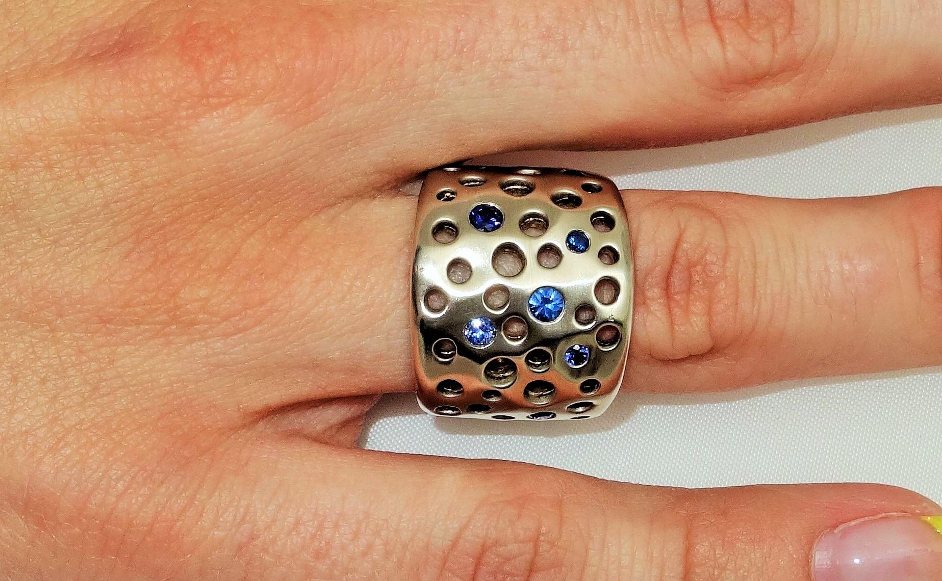 Beautiful Dome Ring features bezel set Blue Sapphires; weighing approx. 0.60tctw; Hand crafted in Rhodium Sterling Silver; the top dome of ring measures approx. 1 inch in length x 0.75 inches wide. Ring size 8. Bold yet unmistakably Feminine!