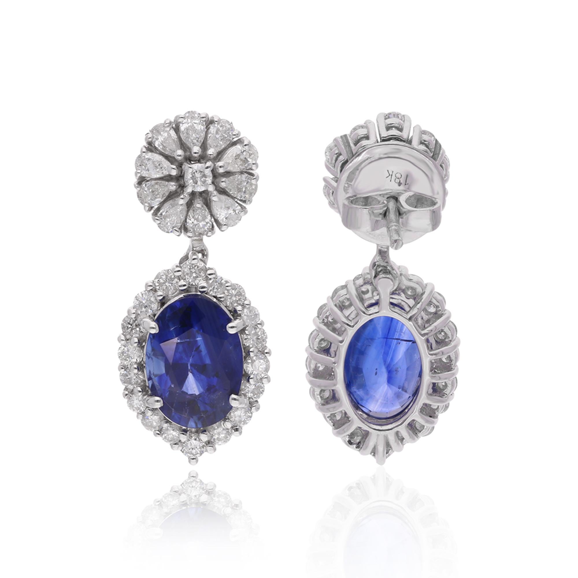 Ces magnifiques boucles d'oreilles pendantes en diamant et saphir sont le parfait mélange des styles classique et contemporain. Réalisée en or blanc massif 18 carats, chaque boucle d'oreille est ornée d'un superbe saphir entouré d'un halo de