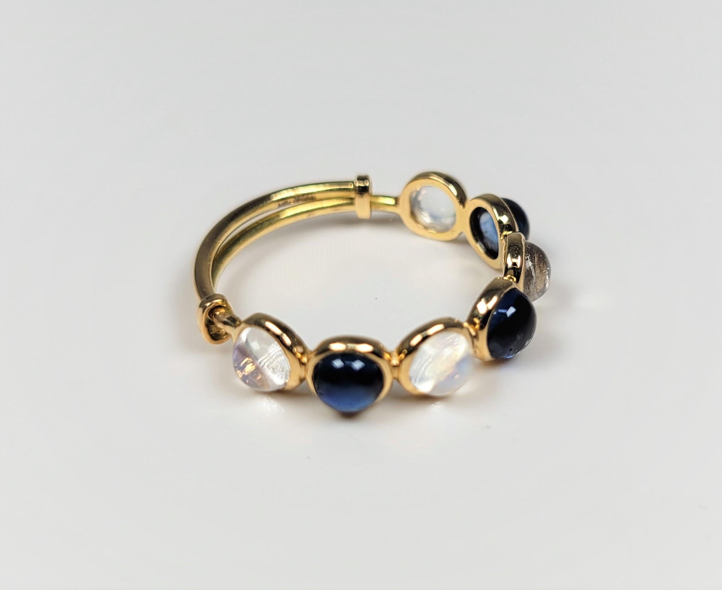The soft blues of the cabochon-cut moonstones pair wonderfully with the cabochon-cut blue sapphires in this 18 karat yellow gold ring. 