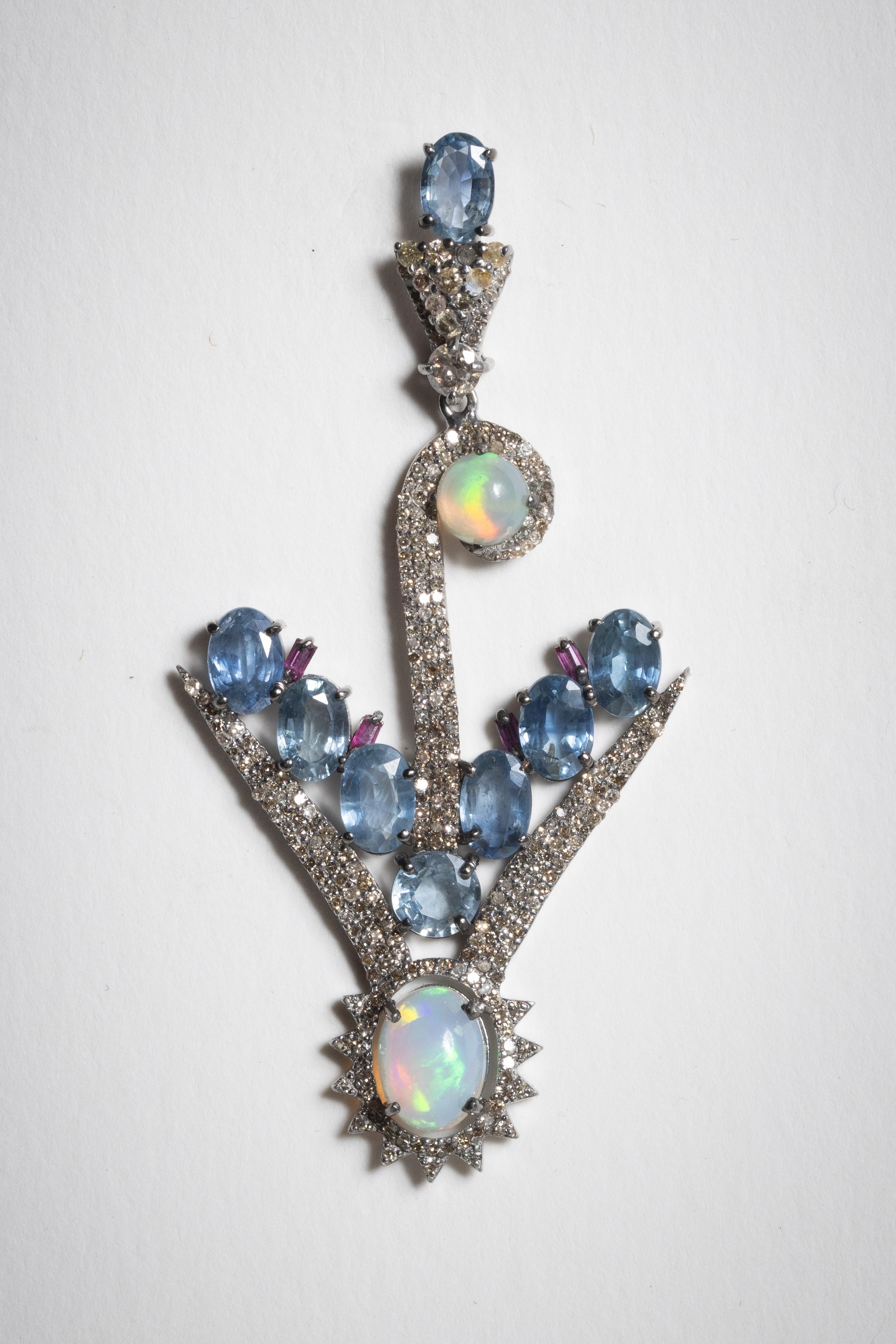 An unusual pair of dangle earrings featuring faceted, oval Ceylon Sapphires (that lighter blue) with brilliant opals and a multitude of round, brilliant cut diamonds in a pave` setting.  Set in sterling silver with 18K gold post for pierced ears. 