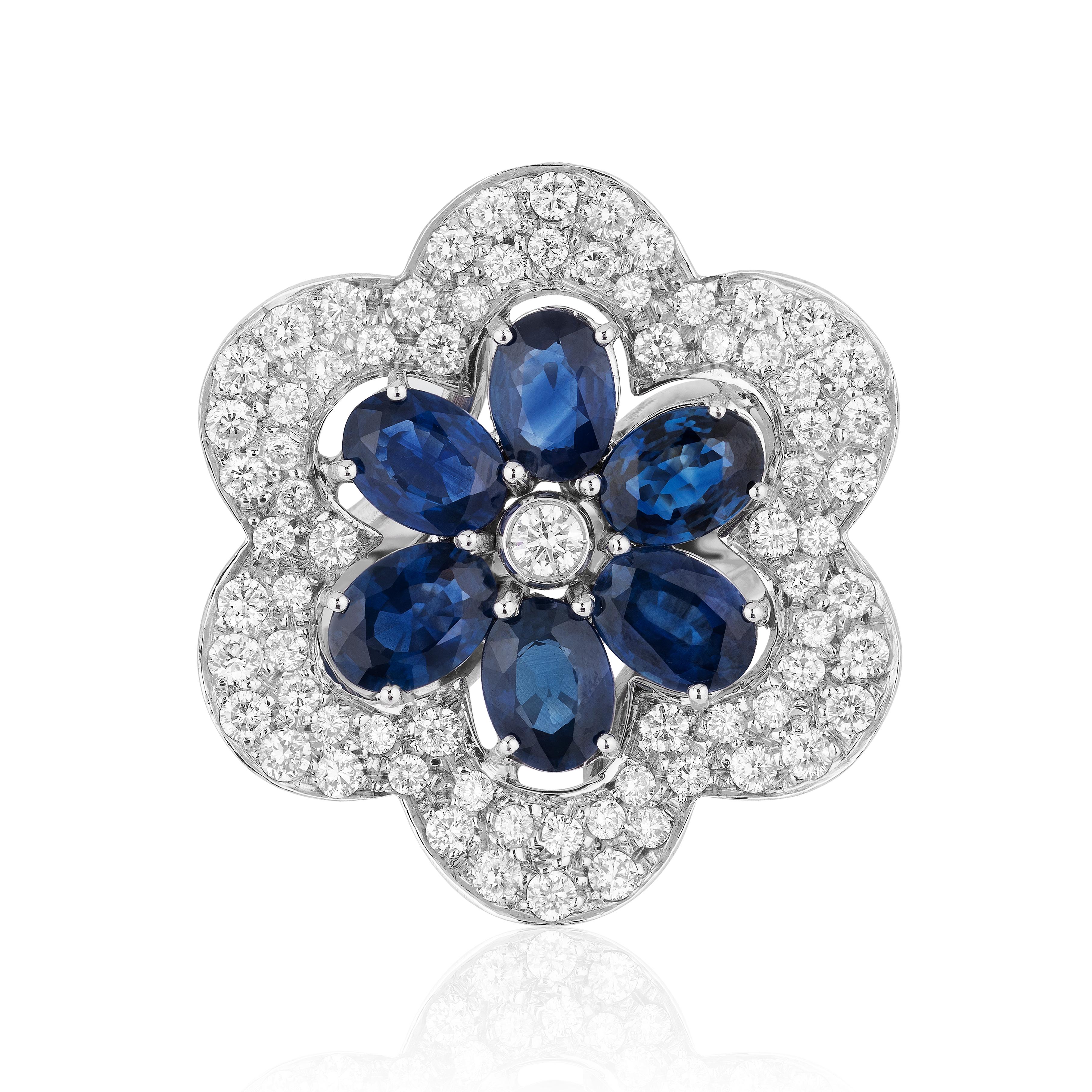 Blue Sapphire Oval and Diamond Flower Cocktail Ring in 18 Karat White Gold. This ring features Six Oval Blue Sapphires from the legendary mines of Kanchanaburi, Thailand weighing 5.42 carats surrounded with 1.86 carats of F-G-H Color VS-SI Clarity