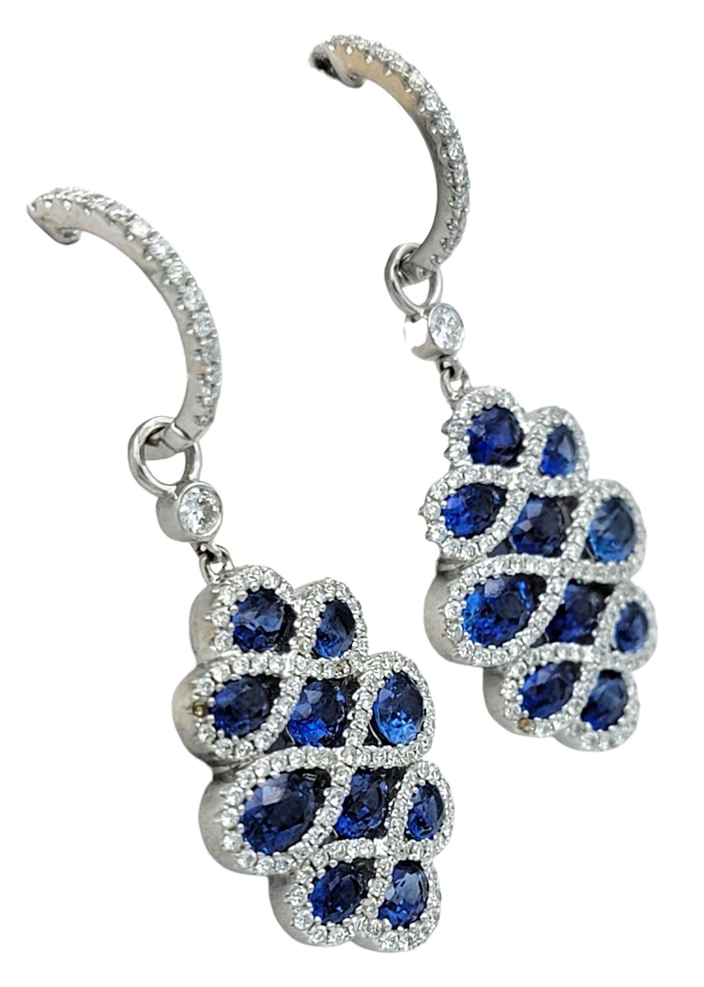 Questi straordinari orecchini pendenti sono realizzati in lussuoso oro bianco 18 carati e presentano un motivo scultoreo a strati. File di zaffiri ovali blu intenso si alternano a scintillanti diamanti rotondi, creando un effetto a spirale che