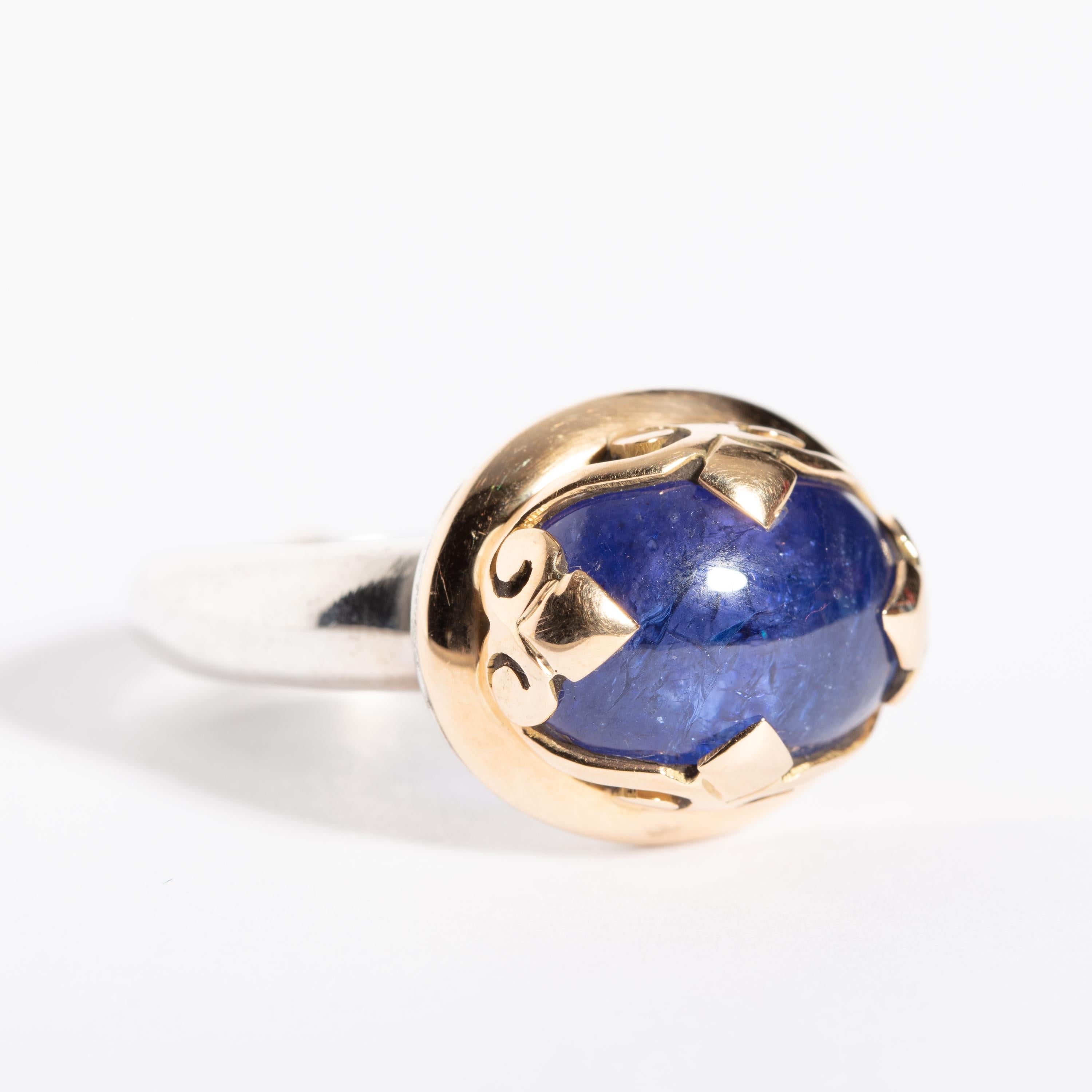 A cabochon blue sapphire set in an unusual 18K solid gold bezel setting; the rest of the band is in sterling silver with an 18K gold 'bead' on the bottom.  Unclear as to the purpose of the bead, but almost has a meditative quality about it.  Ring