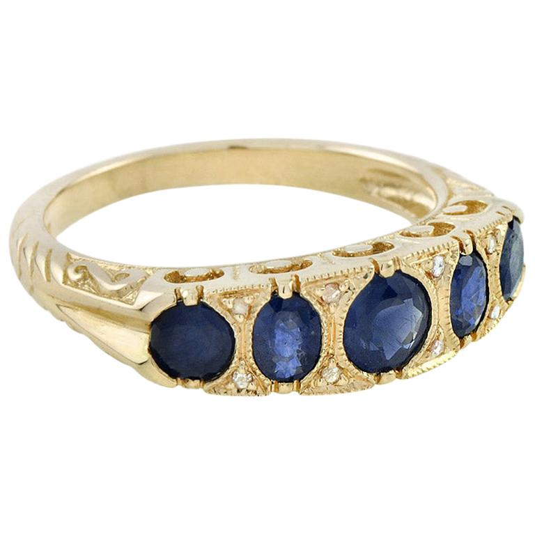 This classic antique 14K yellow gold ring was crafted in English Victorian style. It features five blue sapphires in an intricately set gold gallery. Diamonds are complemented by eight rose-cut diamond points. Decorative shoulders lead to a plain