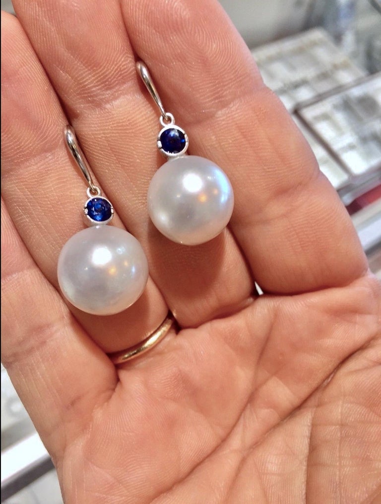 A stunning pair of dangle drop dangle South Sea pearl earrings set with a stunning royal blue sapphire 1.10 carat.
Natural Round Cultivate White South Sea Pearls
Surface : Thick Nacre with Natural Flaws
Pearl Measurements :  14mm 
Other Stone : 100%