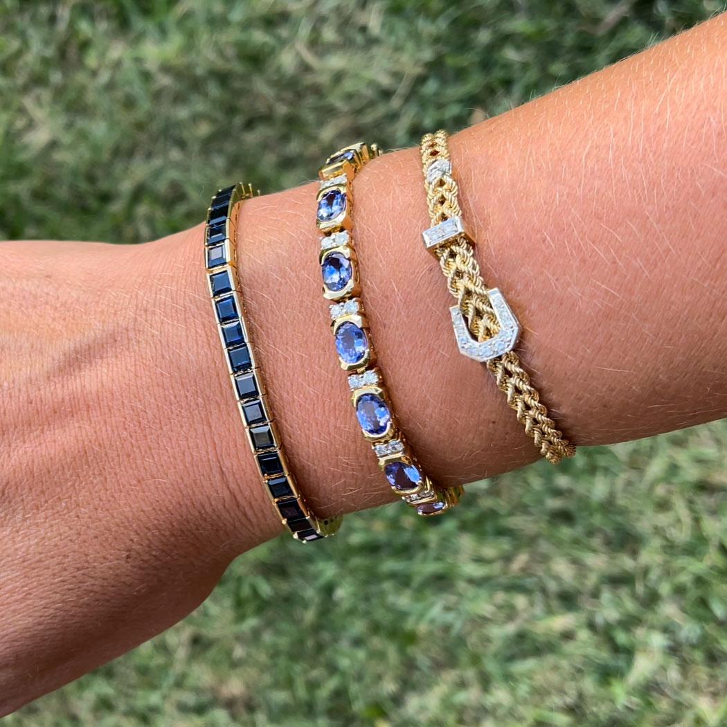 Bracciale tennis con zaffiro blu in oro giallo 14k. Questo bellissimo bracciale presenta 42 zaffiri blu quadrati tagliati a gradini incastonati. Ogni zaffiro misura circa 4,00 mm x 4,00 mm per un totale di circa 14,50 carati. Gli zaffiri hanno un