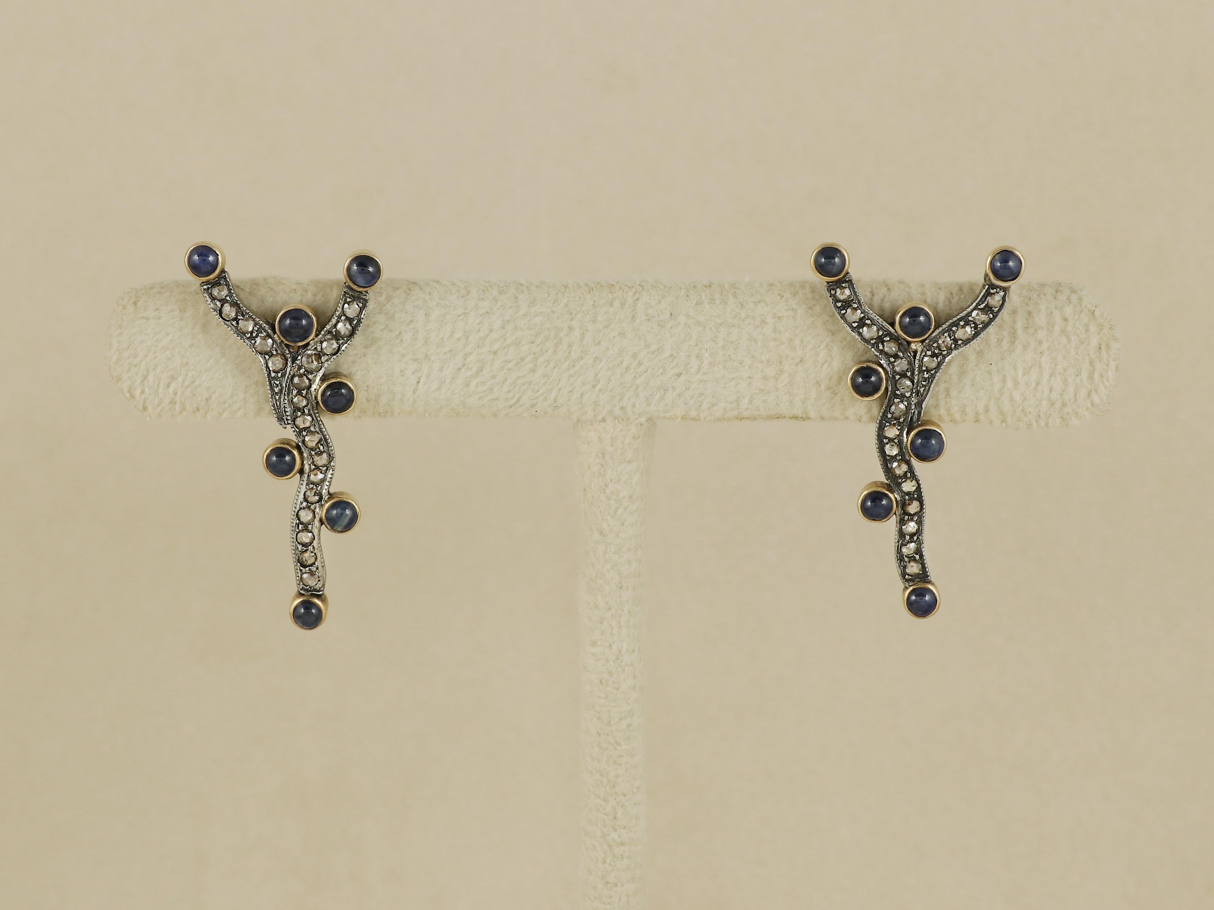 Ces charmantes boucles d'oreilles de style victorien offrent une interprétation délicate et complexe des bijoux anciens. Le point focal de chaque boucle est un arrangement captivant de sept saphirs bleus ronds naturels, méticuleusement sertis pour