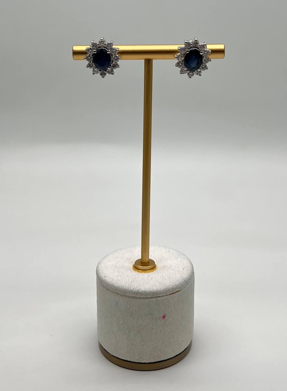 Enhance your elegance with these stunning earrings. Featuring deep blue sapphires surrounded by a halo of sparkling clear diamonds, these earrings are perfect for any sophisticated event. Intricate, timeless, and refined.