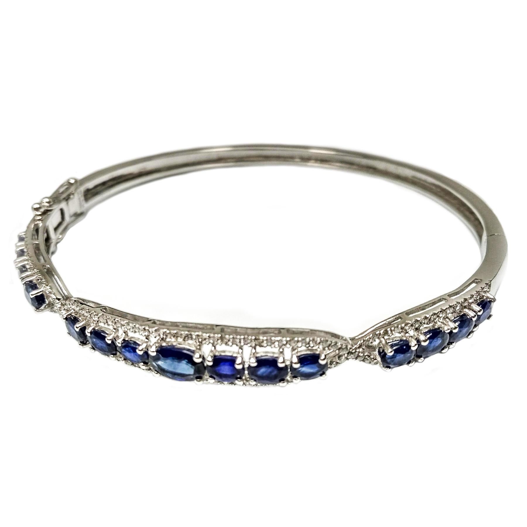 Elegant sapphire and diamond bangle. Contemporary handcrafted single row, dark blue, 3.74 carats, oval faceted sapphire mounted with head prongs. High polished bangle accented with round brilliant cut diamonds, set in 14 karat white gold, with