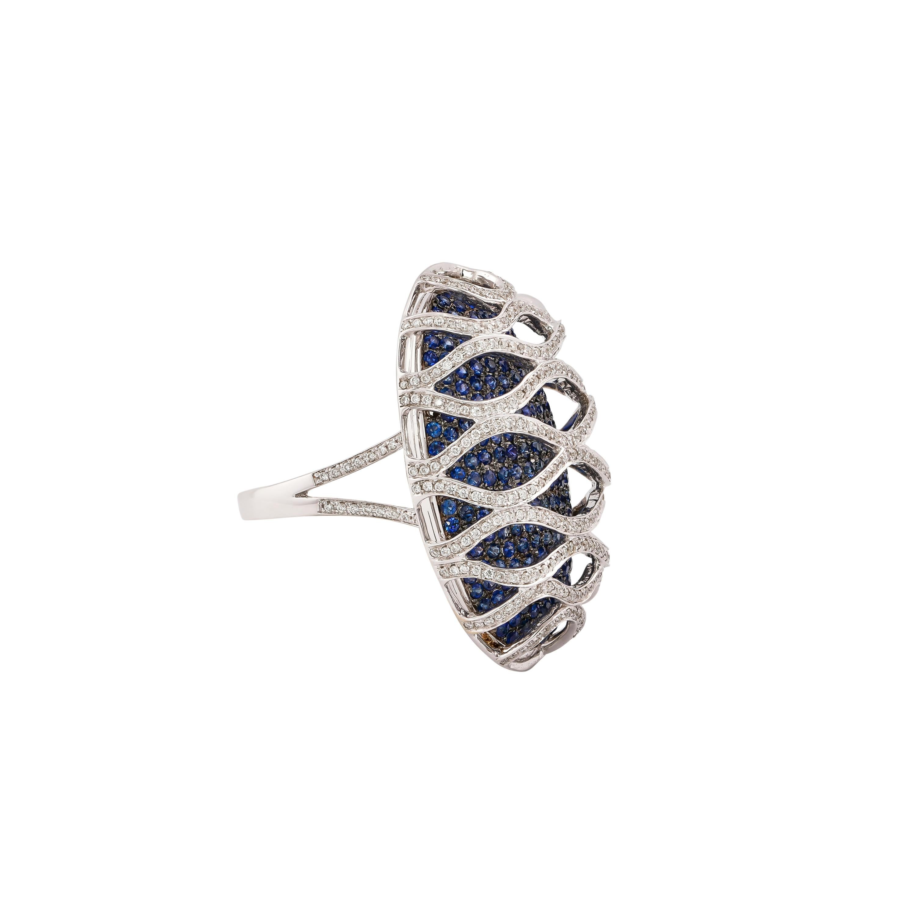 Sunita Nahata presenta una colección de elegantes anillos de cóctel con preciosas piedras preciosas. Este anillo utiliza una base pavé de zafiro azul con una jaula de diamantes de construcción arquitectónica en la parte superior. Este diseño único y