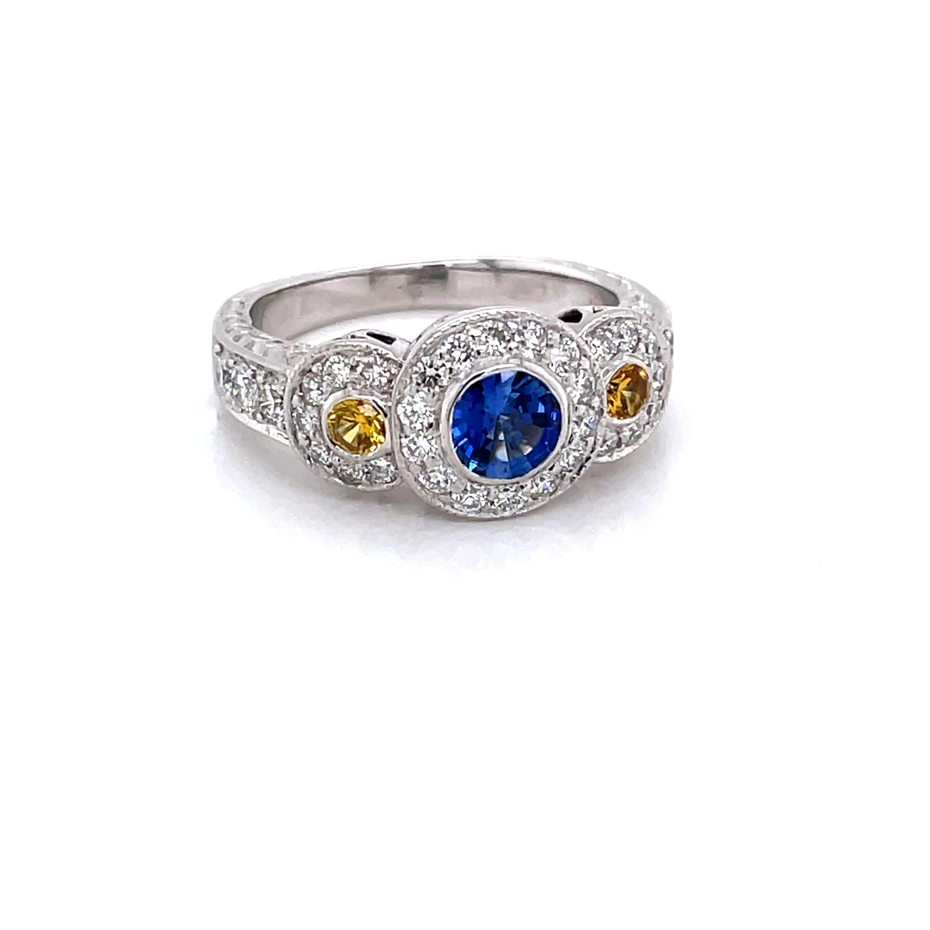 Vivid blue and yellow strongly saturated sapphires animate the beauty and sparkle of this triple halo diamond engagement ring in eighteen karat 18K white gold. One bezel set round faceted blue-violet .73 carat sapphire is featured at center and