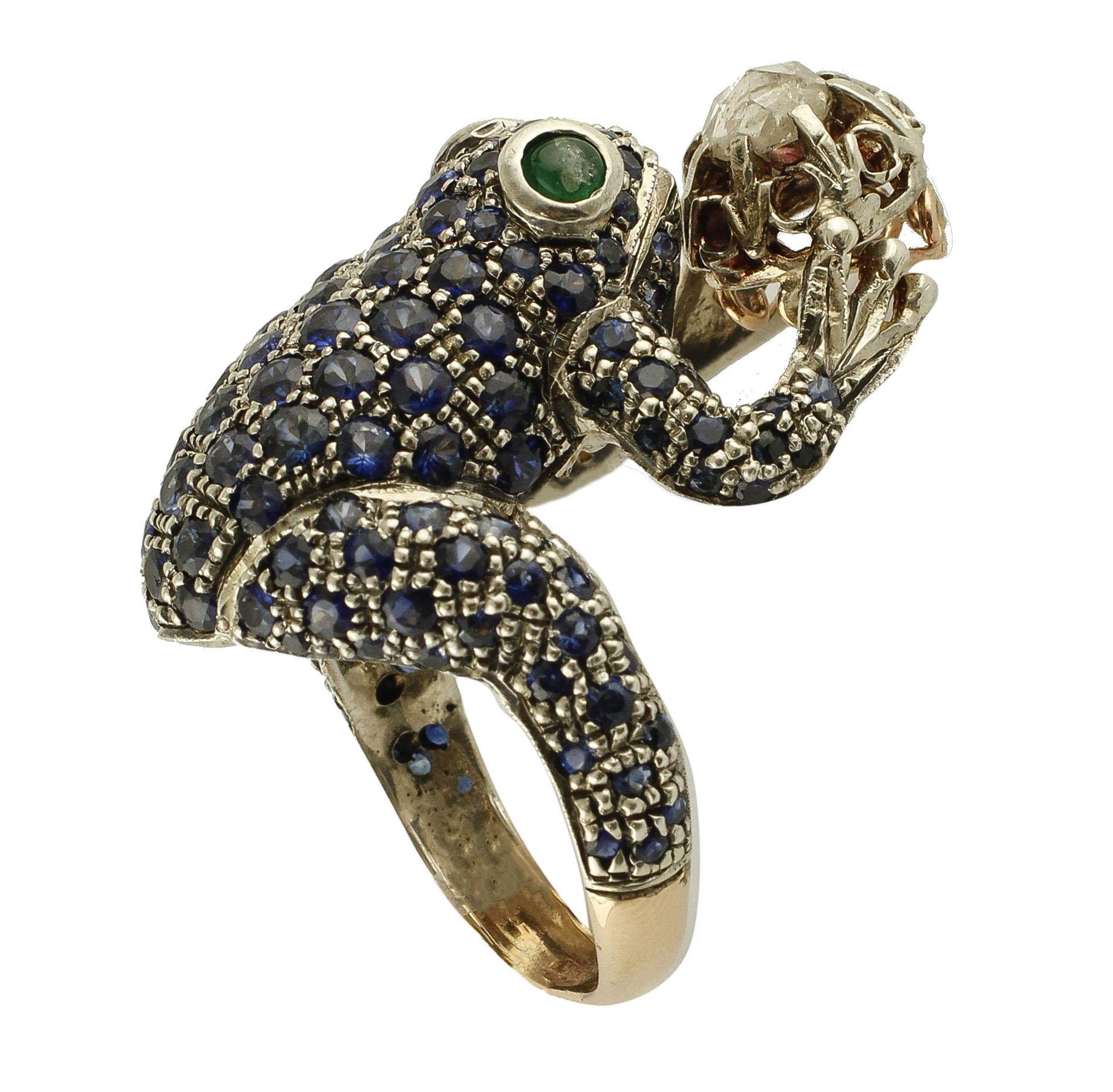 Beautiful ring in gold and silver structure with frog design. The frog 's body is studded with blue sapphires, while the crown that the frog is holding has a diamond on the top. 
This ring is totally handmade by Italian masters goldsmths
Diamonds