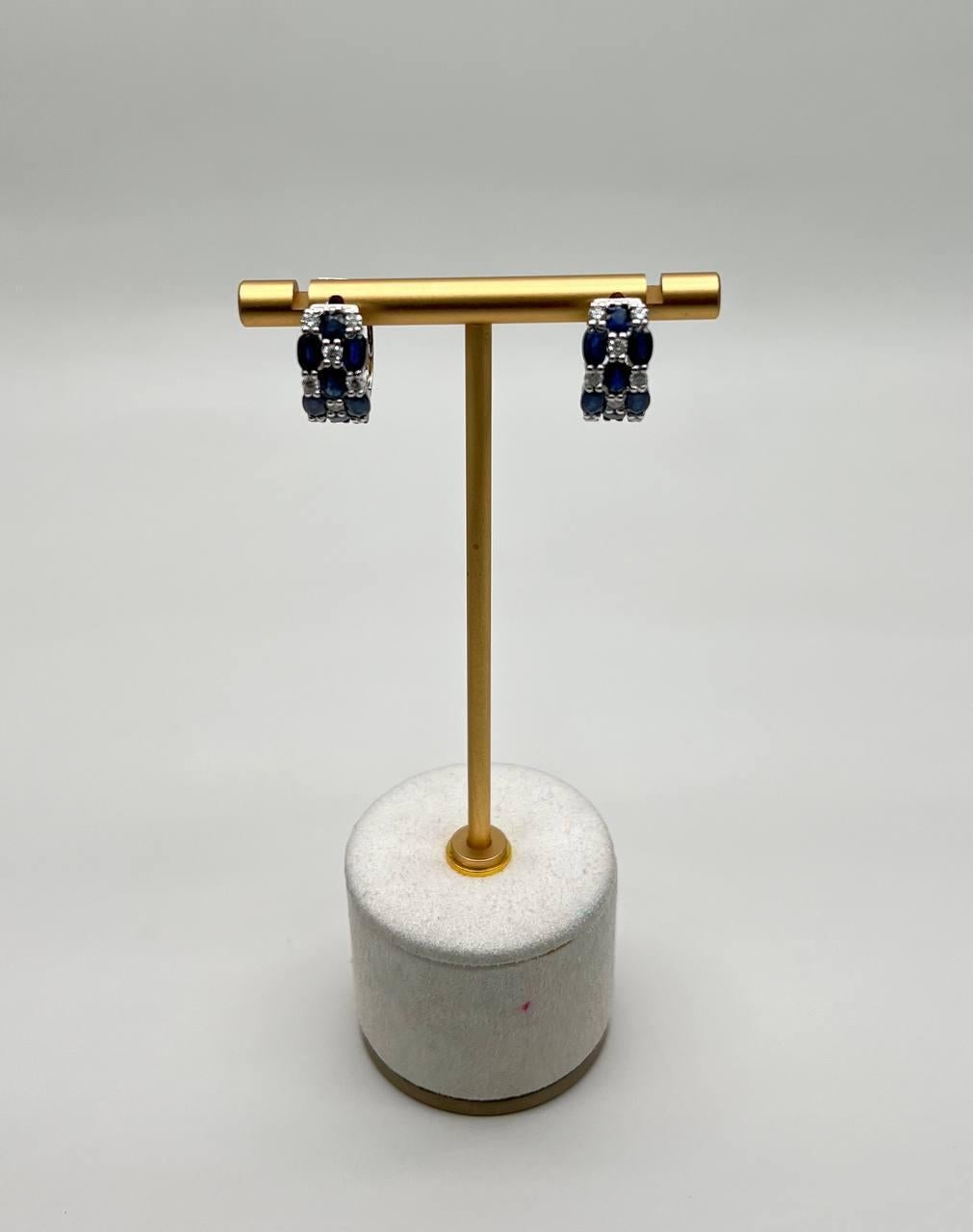 Crafted with precision, the earrings feature deep blue sapphires that exude sophistication and charm. The intricate design is both modern and elegant, making them a perfect accessory for any occasion. 14K White Gold. 0.63 CTW Diamonds. 4.09 CTW Blue