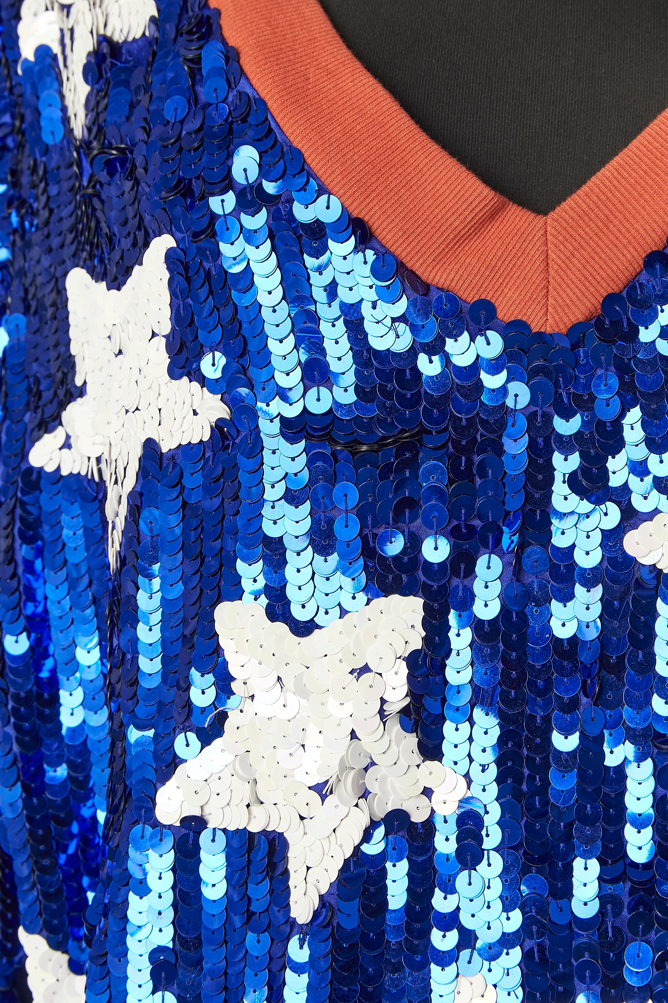 Blaues Paillettenkleid mit weißem Sternpaillettenmuster . Zusammensetzung des Stoffes: 100% Polyester. Die Rückseite ist aus einfachem Polyester-Satin. Orangefarbenes Baumwollband am Halsausschnitt, am unteren Rand und am Ärmelrand 
GRÖSSE 40 / L 