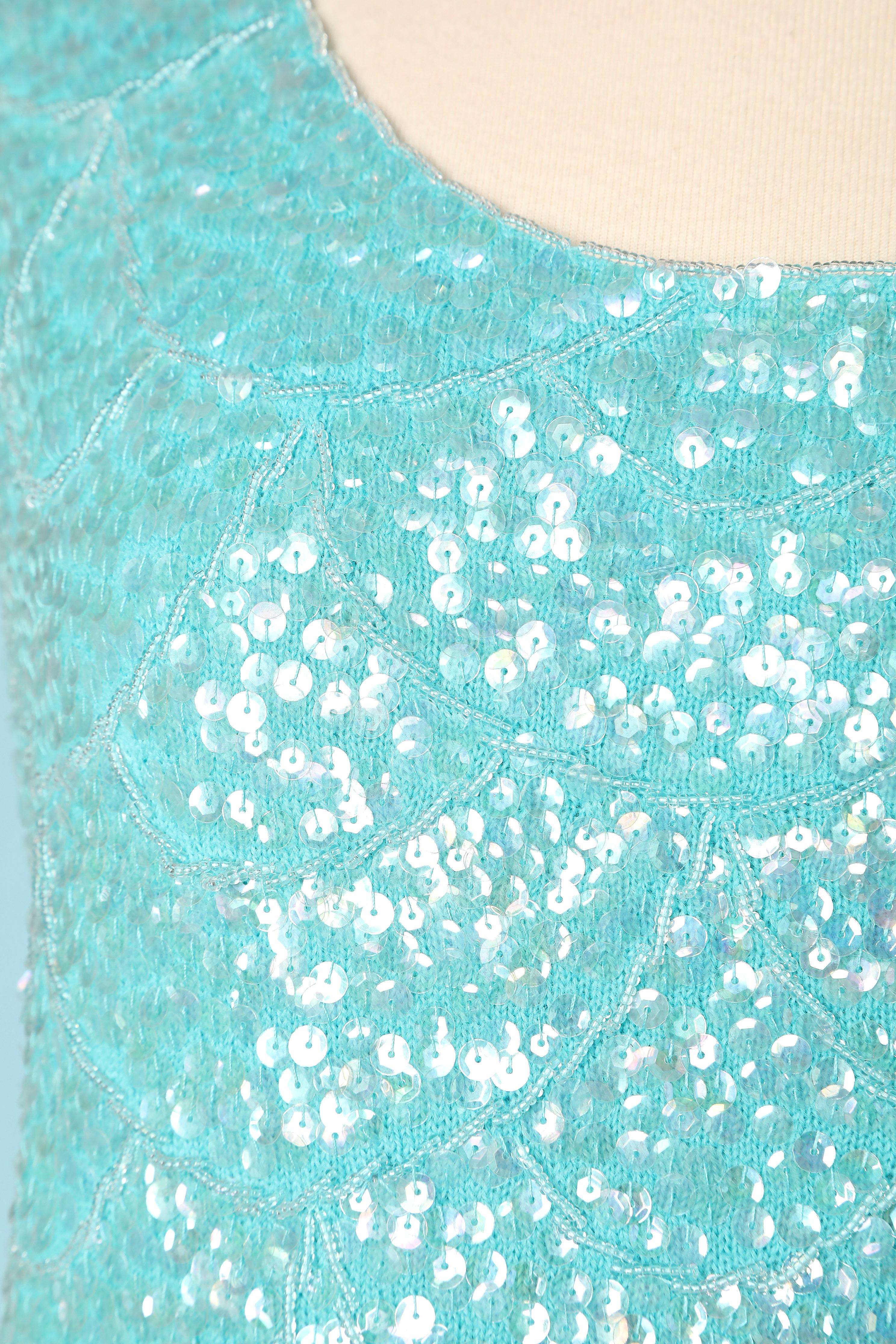 Top bleu sans manches avec perles sur base de tricot. Doublure en acétate. Fermeture à glissière au milieu du dos. 
TAILLE L 