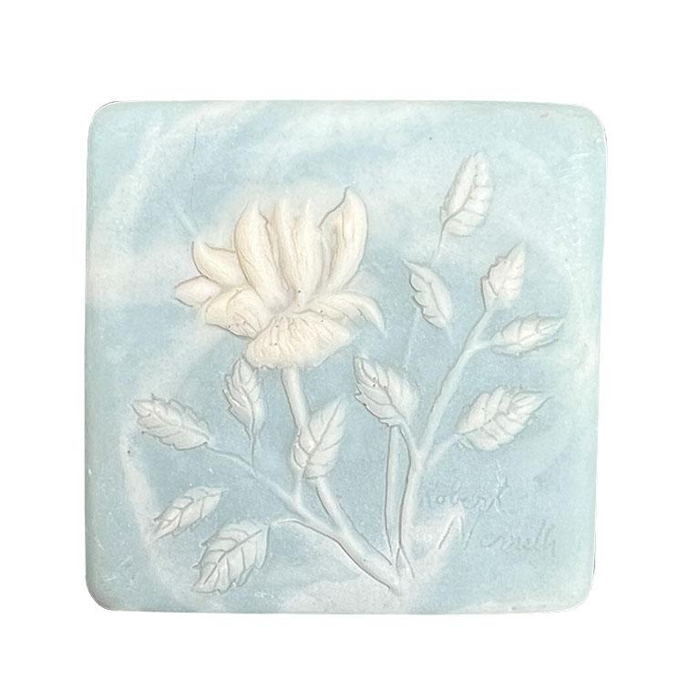 A small square trinket box in blue, with a floral lid. Signed by the artist, Robert Nemith for Design Gifts. This would make a great piece for a dressing table or nightstand to hold jewelry.  

Dimensions:
2.5