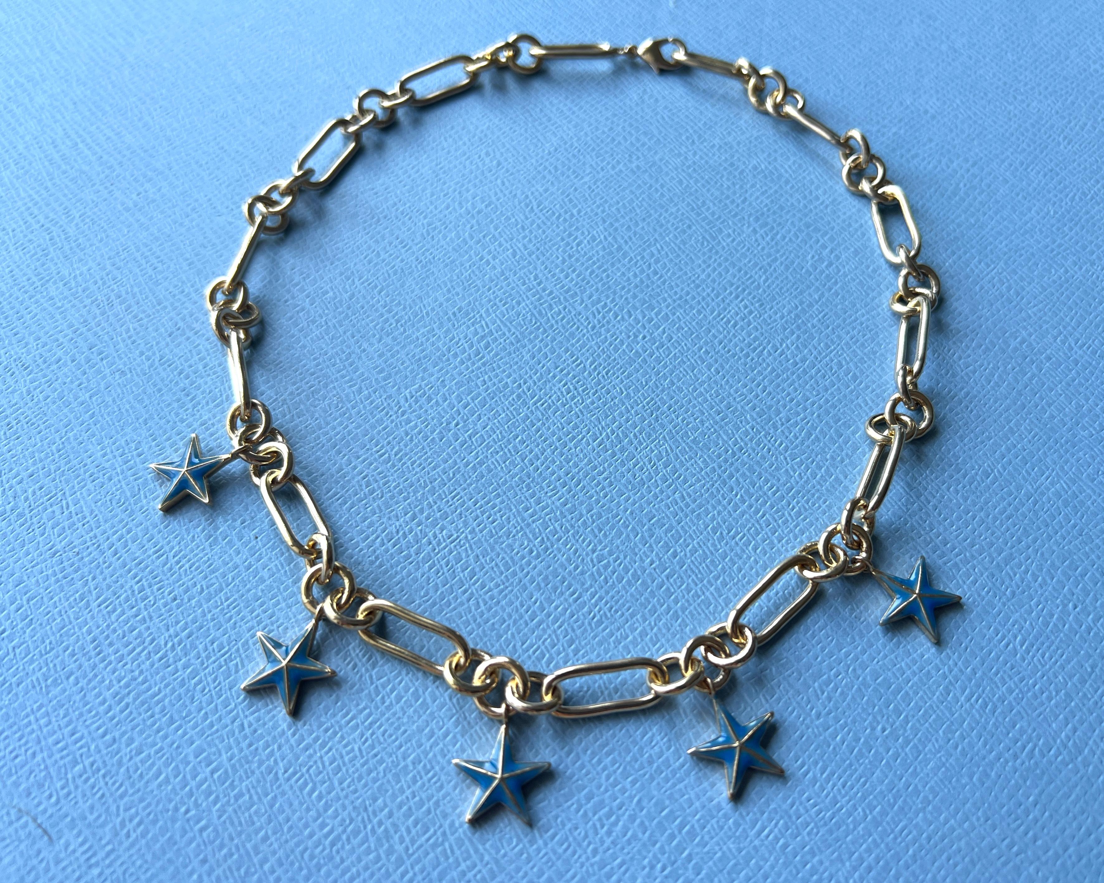Collana a catena girocollo con ciondolo a 5 stelle in oro 14k e blu trasparente  Smalto dipinto a mano su ogni stella

La stella a cinque punte, spesso conosciuta come pentagramma, racchiude un importante simbolismo spirituale in diverse tradizioni
