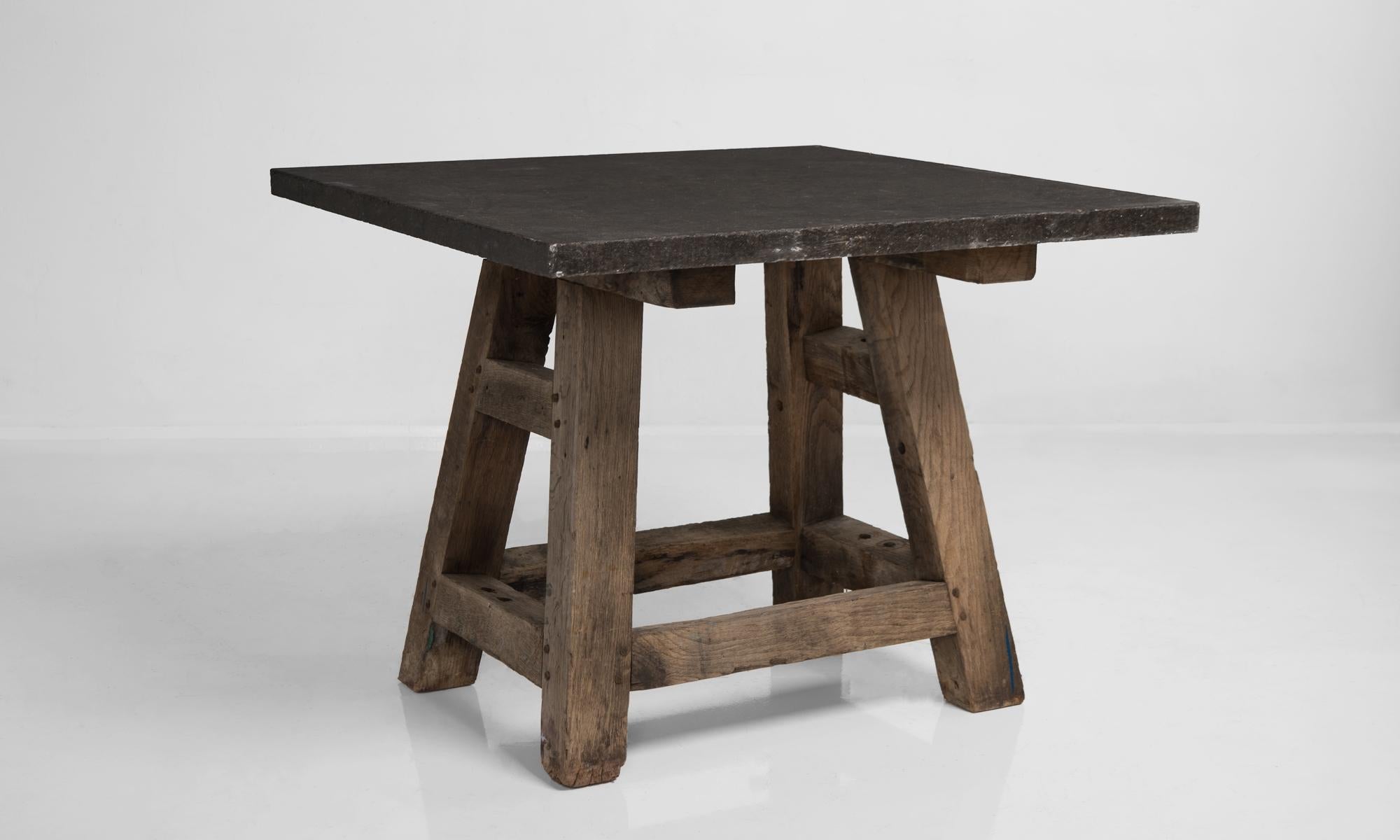 Blue stone workshop table, France, circa 1930.

Unique square-top industrial table with thick wood legs and beautiful stone top.