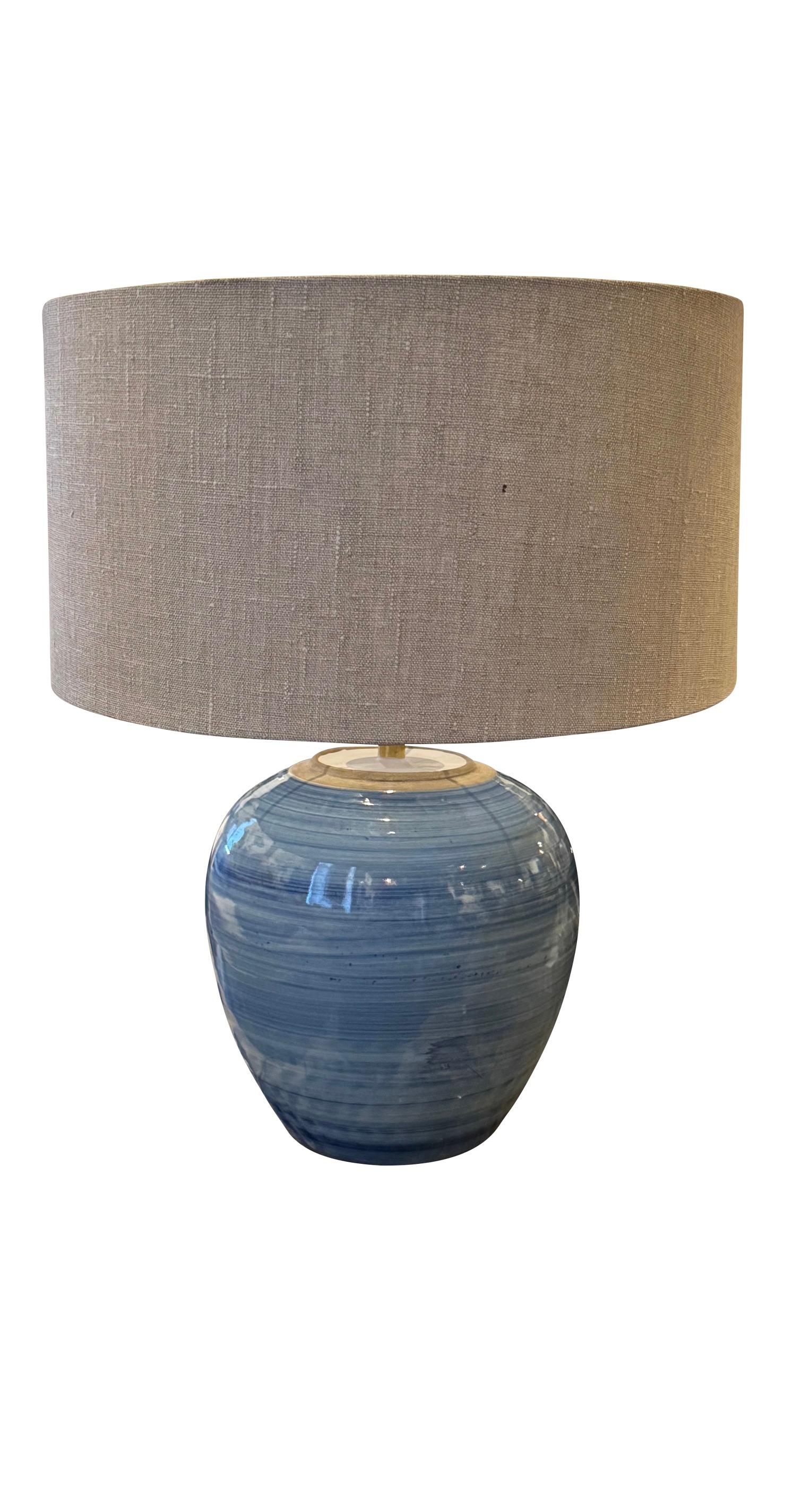 Contemporary Chinese pair round shape with 
striated horizontal blue glaze.
Belgian linen shades included.
Single also available. L1181
Base measure 10