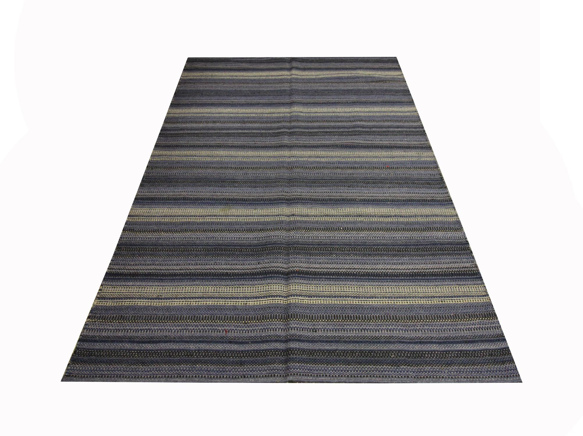 This bold area rug is a flat woven kilim, woven by hand in the early 21st century. The design features a simple stripe pattern woven in accents of blue, cream and black. The colour and the design make this piece the perfect accent rug for both