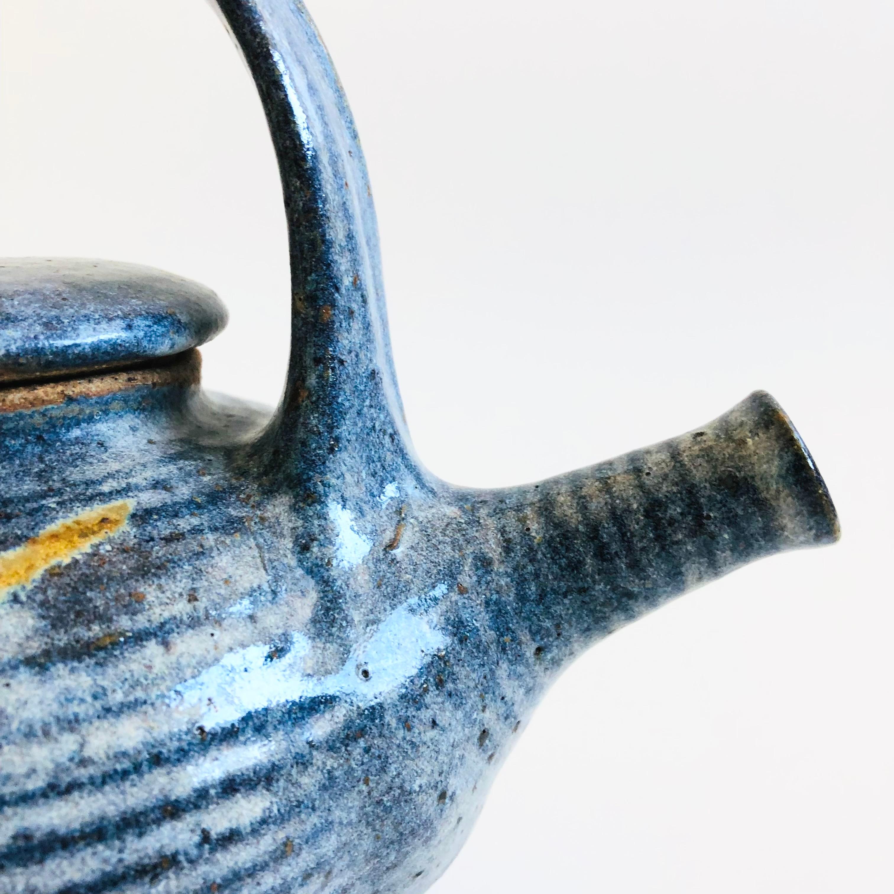 Una tetera vintage de Studio Pottery. Precioso esmalte azul apagado moteado con un diseño abstracto pintado a mano en cada lado. Firmado en la base.

