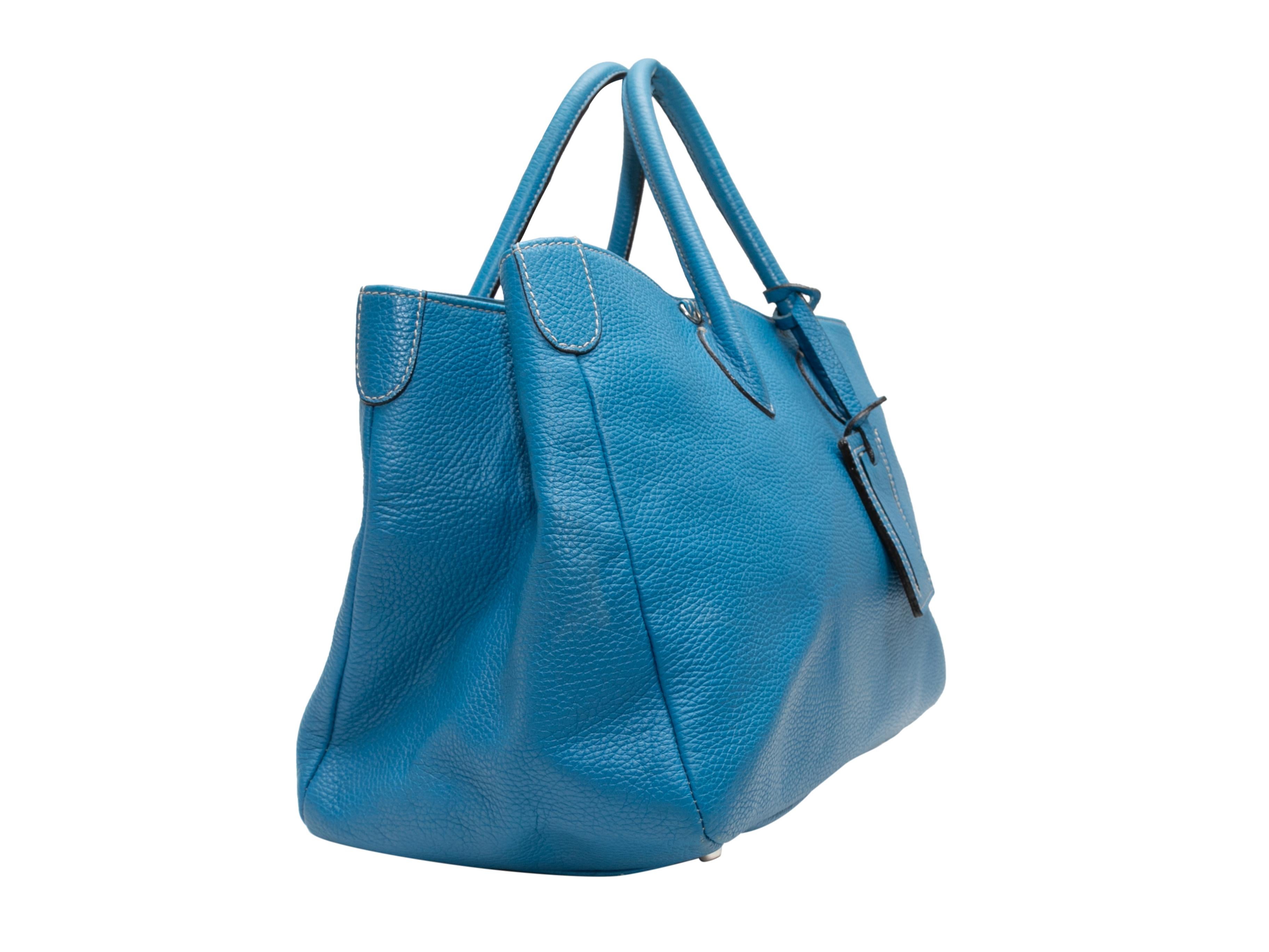 Blue Suarez Leather Crossbody Tote Bag. This crossbody tote bag features a leather body, silver-tone hardware, dual rolled top handles, and a flat beige crossbody strap. 14