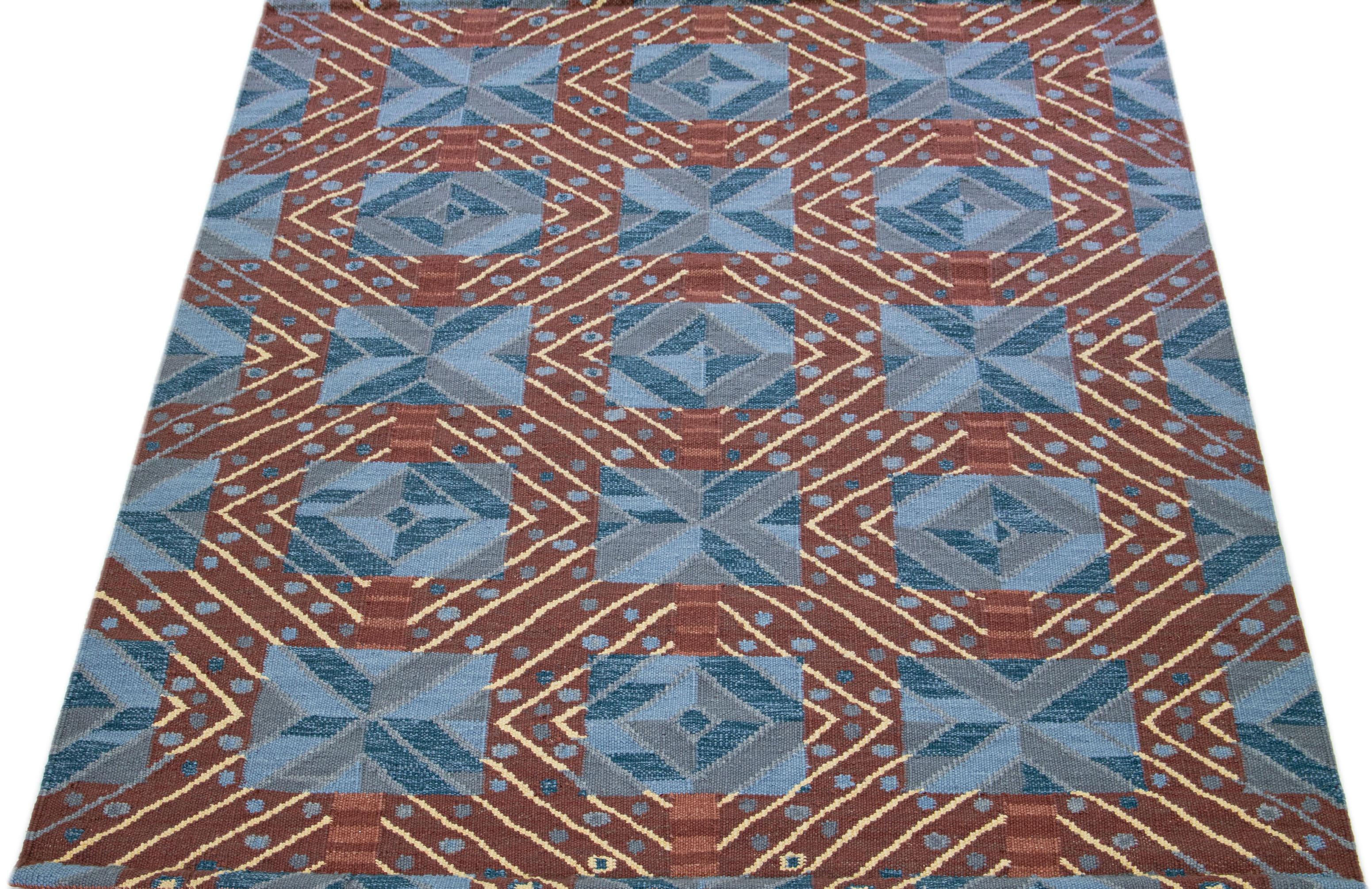 Featuring a captivating blue backdrop, this modern wool rug takes inspiration from the refined Swedish design. The attractive brown geometric pattern further enhances its exquisite beauty, making it a magnificent display of Swedish-style